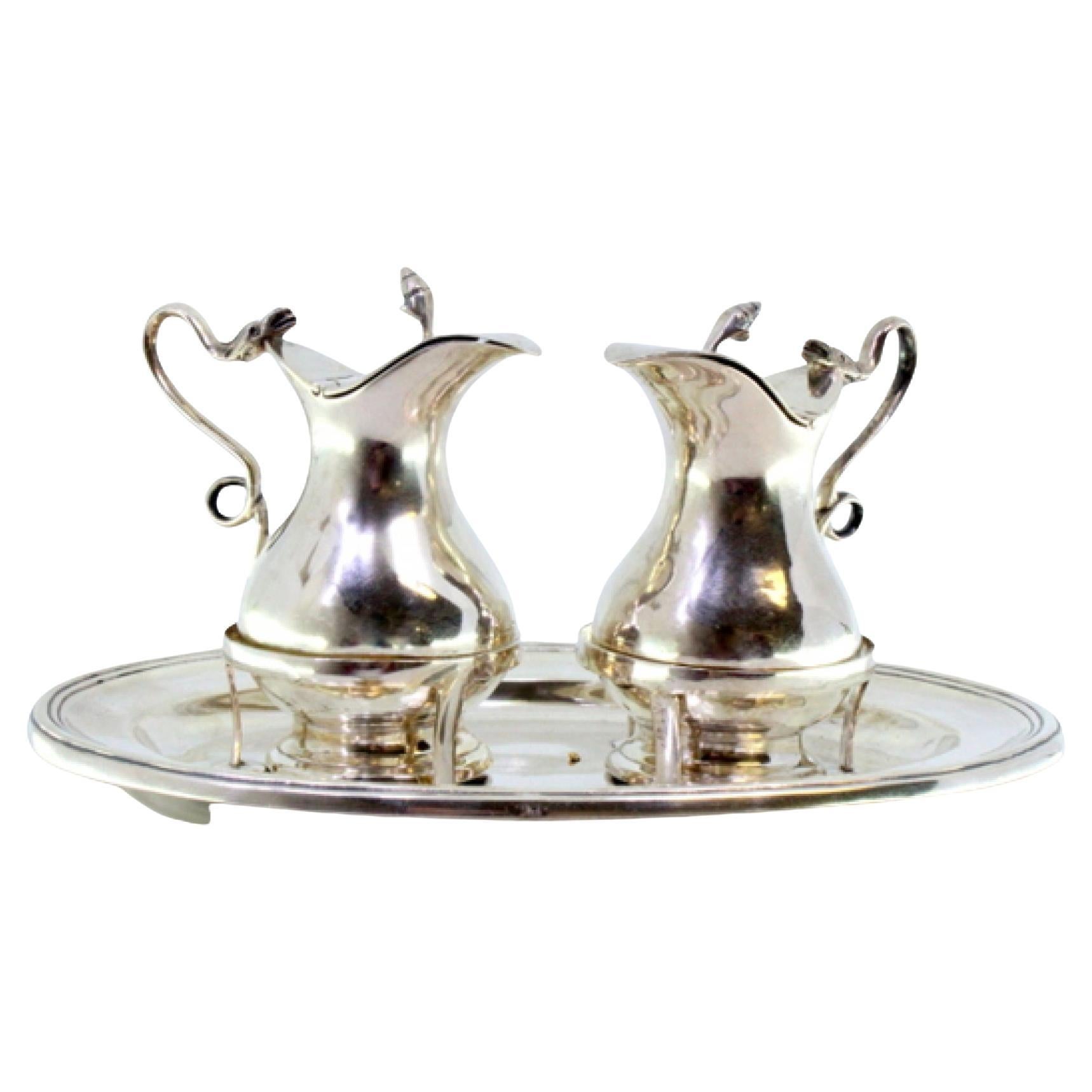 Silver altar cruets with lid knobs on elliptical base with double frieze