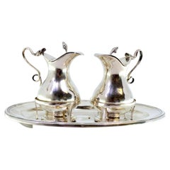 Silver altar cruets with lid knobs on elliptical base with double frieze