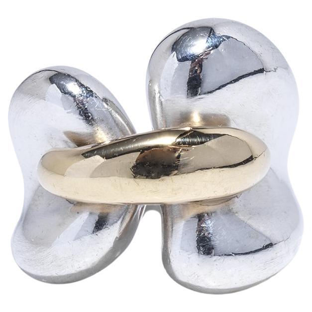 Dieser Ring aus 18 Karat Gold und Silber besticht durch sein markantes Design mit einem breiten Band, das sich nach oben hin allmählich verbreitert und so ein auffälliges Profil schafft. In der Mitte befindet sich ein wunderschönes, goldenes Detail,