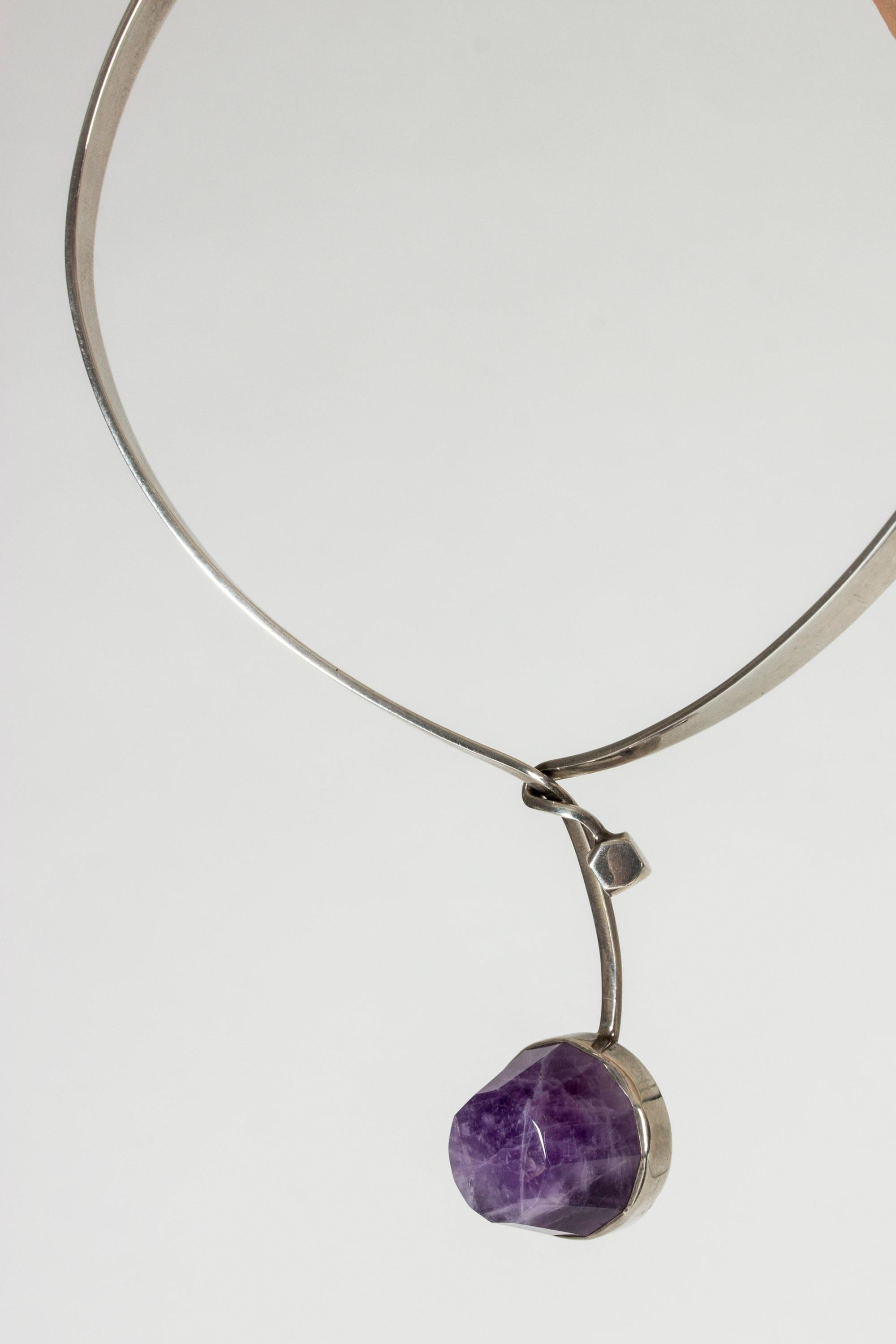 Beautiful silver neckring by Malmö silversmith Gert Thysell. Jeweled with a large amethyst stone with a very original cut, nicely designed opening with the neckring twisting around itself.