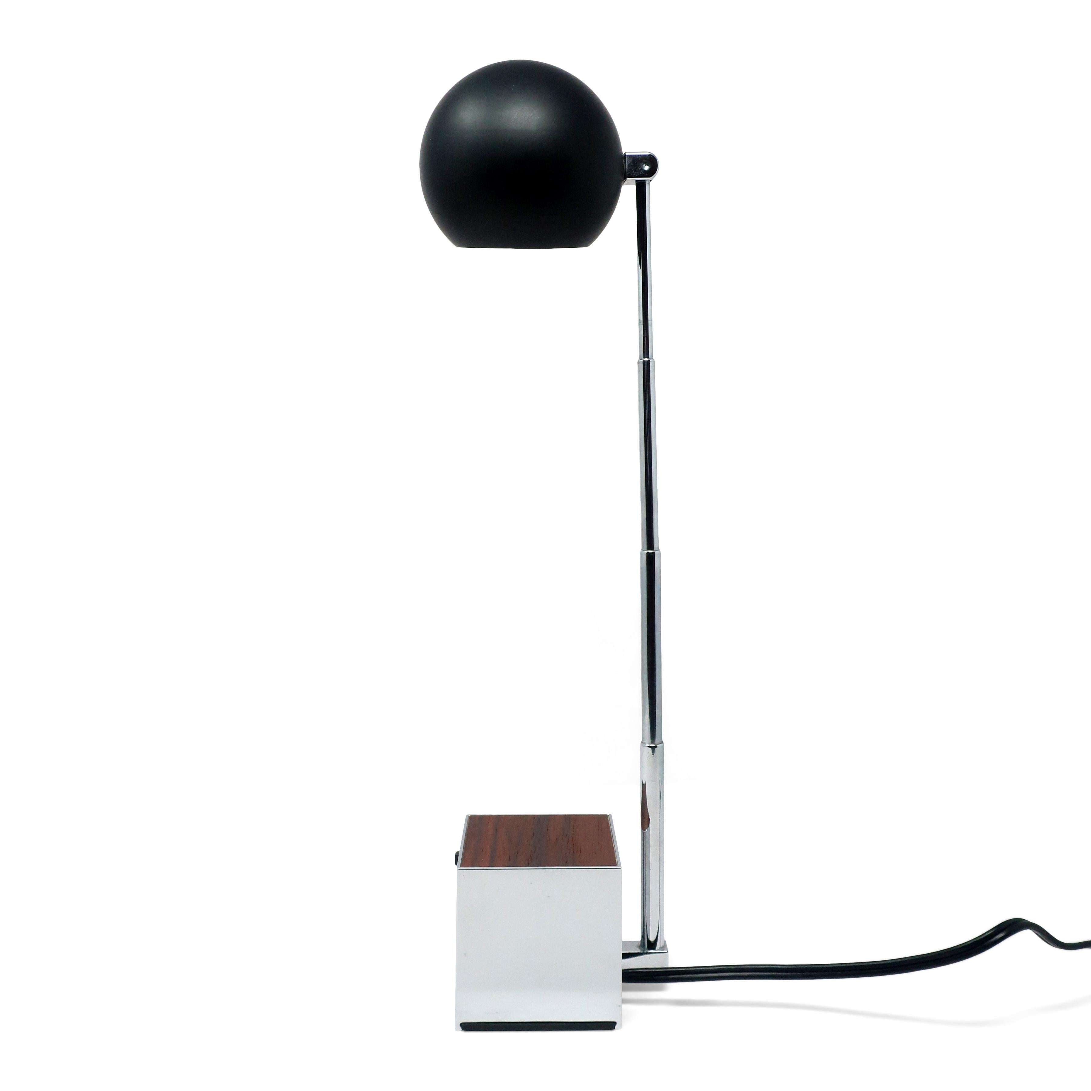 A mid-century modern Lytegem desk/task lamp by Michael Lax for Lightolier (1965) with a chrome base with wood inlay, black shade and extendable chrome stem, with switch for two light intensities.  Can be found in the permanent collection of the