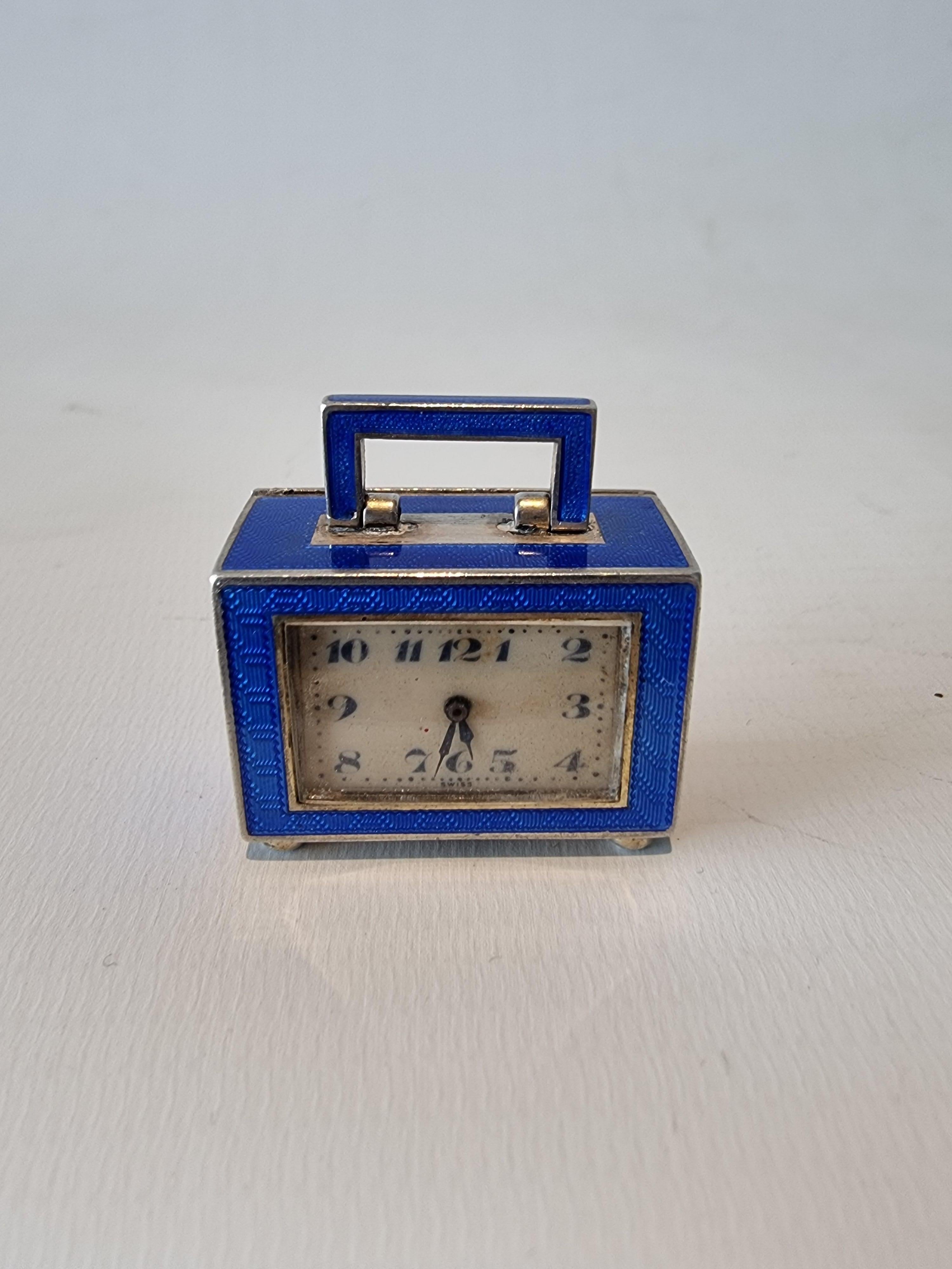 An absolutely tiny and exquisite sub miniature silver and blue guilloche enamel carriage, travel or boudoir clock by Juvenia. Juvenia are a luxury Swiss watchmaker.  Modeled almost as a suitcase, or briefcase, this is the smallest clock we have ever