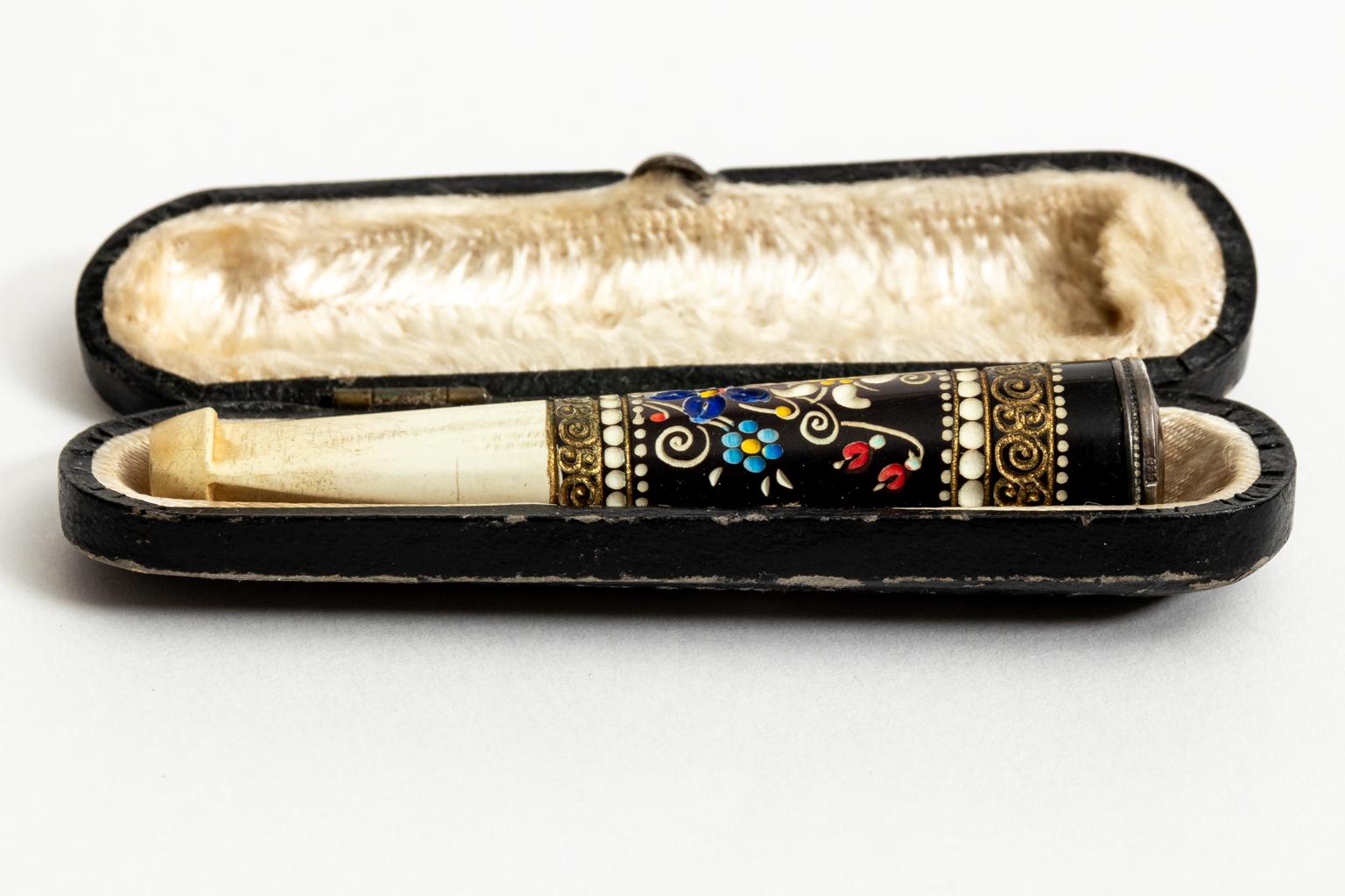 Silver and bone cigarette holder with original case and a top marked 935. The latch of the case is still functional. The piece also features enamel work depicting motifs such as multi-color flowers framed by scroll and bead trim. Made in Austria,