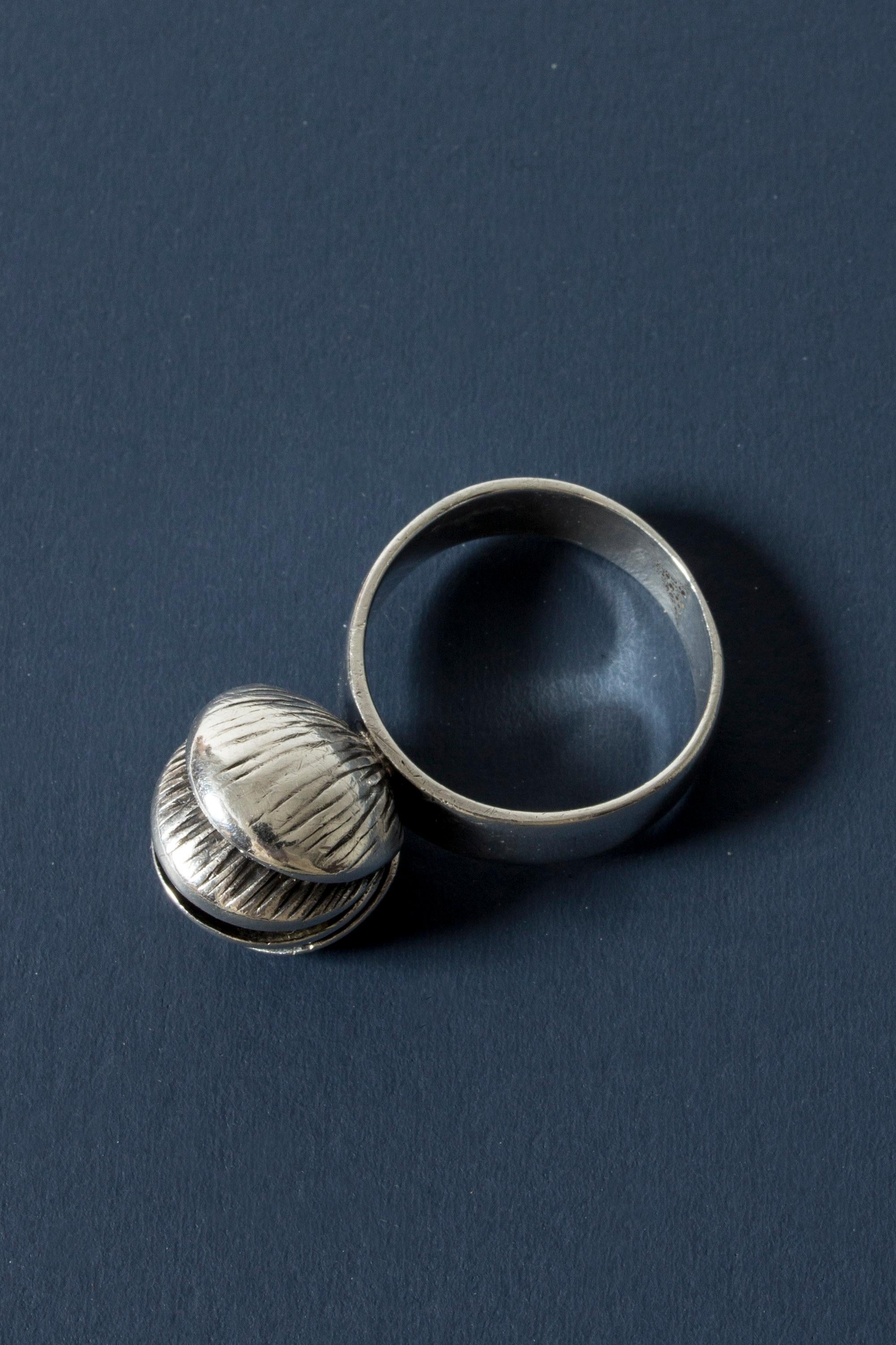 Beautiful silver ring by Elis Kauppi, adorned with a shell-like design. The layers of the shell open up and hidden inside is a round carnelian stone. It is loose inside the shell and tinkles discreetly with movement.