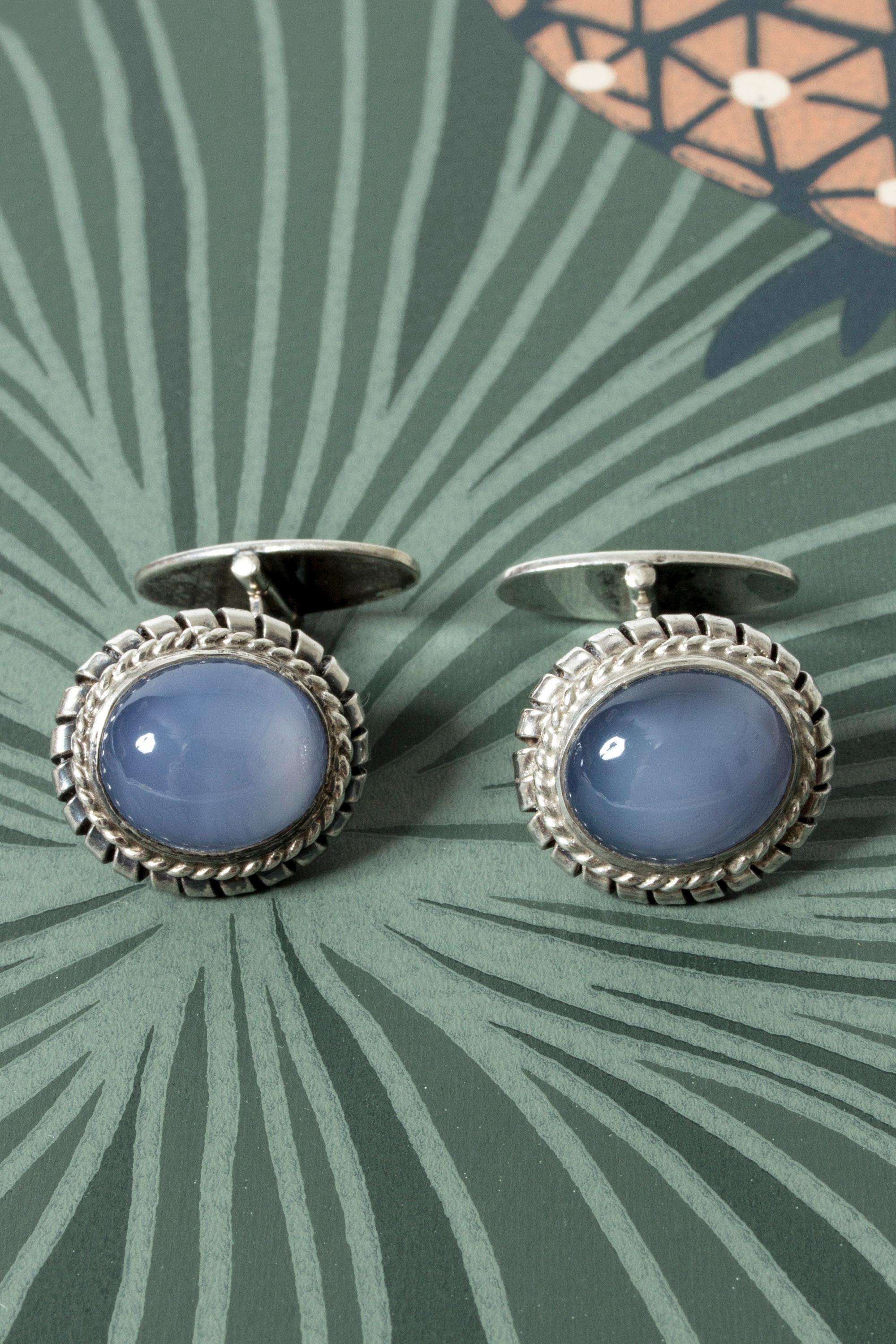 Pair of elegant silver cufflinks, with large, oval chalcedony stones. Ornate frames around the beautiful, sky blue stones.