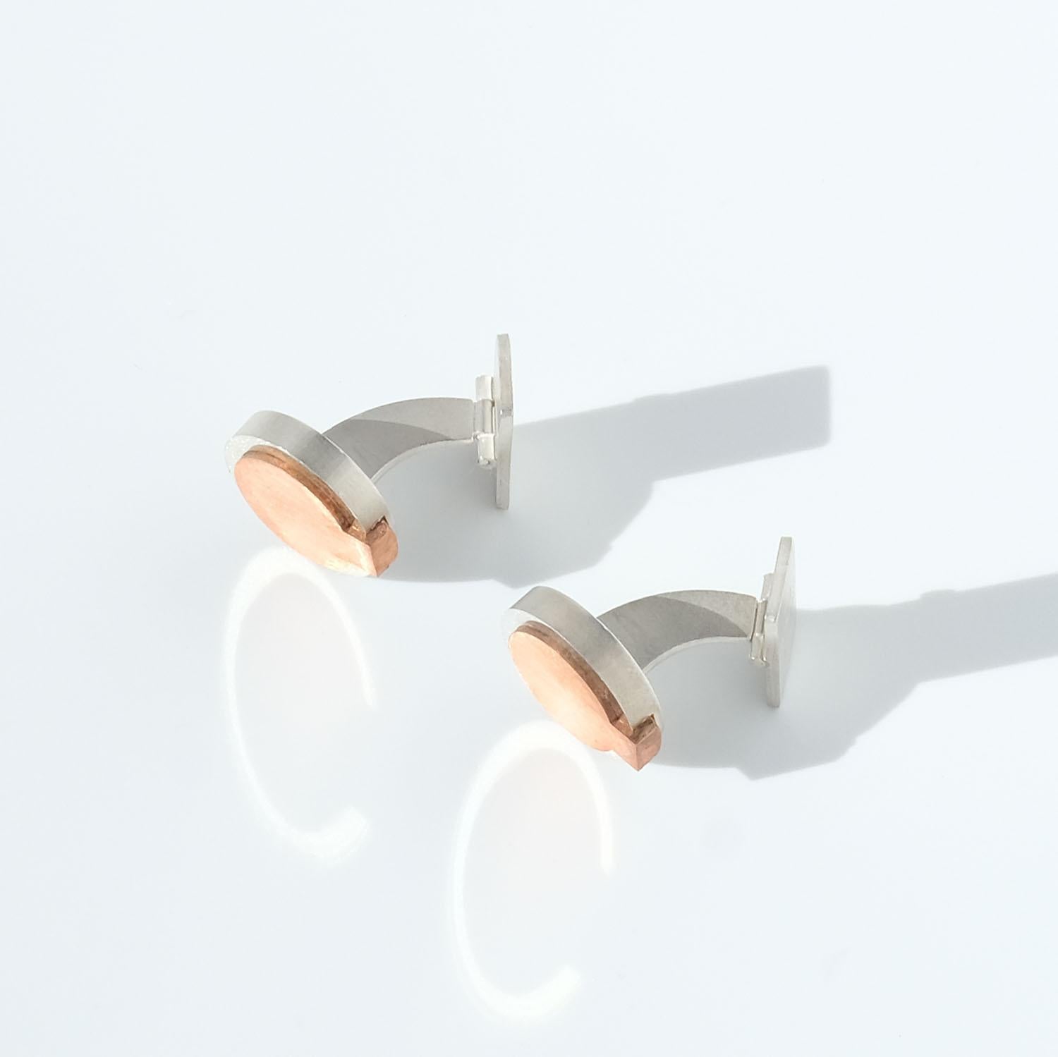 These cufflinks are made out of sterling silver and copper. They have a circular shape and a matte, brushed surface.

A pair of cufflinks like this is suitable for both everyday wear as well as any festive occasion.

The cufflinks were made in 1987