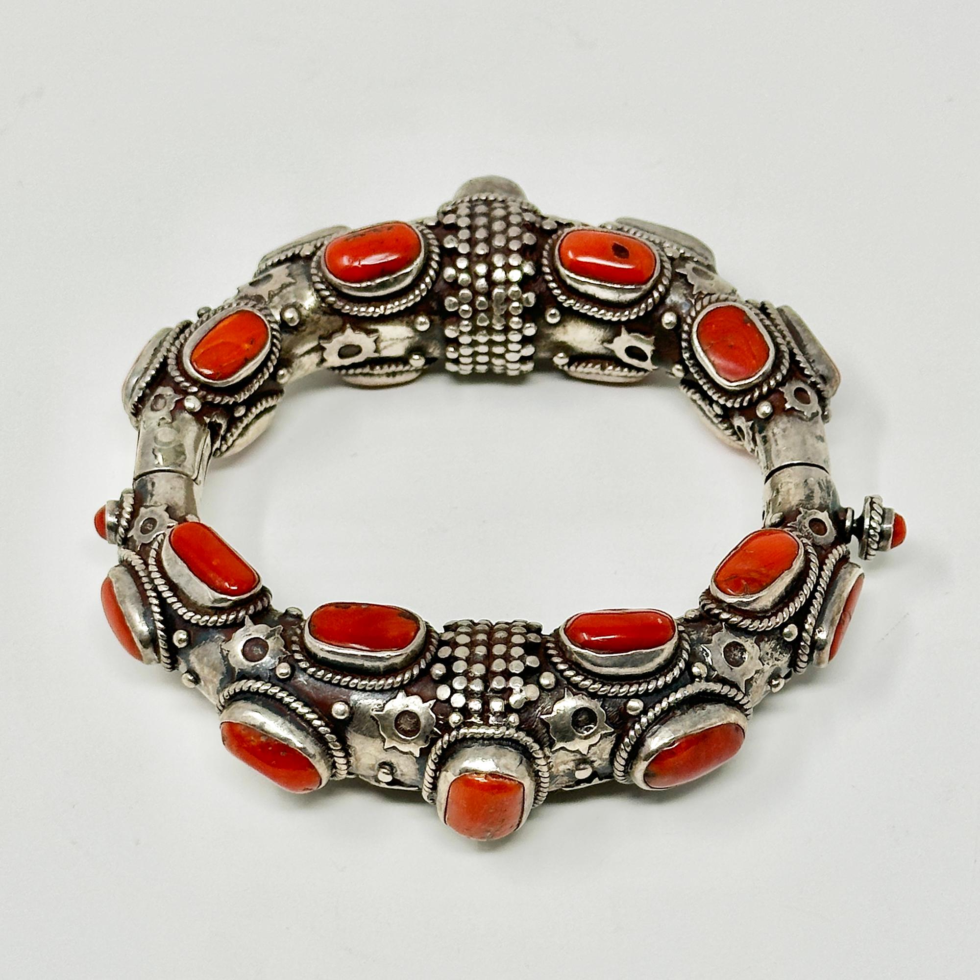 Bracelet en argent et corail clouté du 20e siècle

Magnifique bracelet à charnière en argent et corail fabriqué à Katmandou, au Népal, dans les années 1970. Il y a 26 cabochons de corail authentique sertis dans des biseaux entourés d'étoiles
