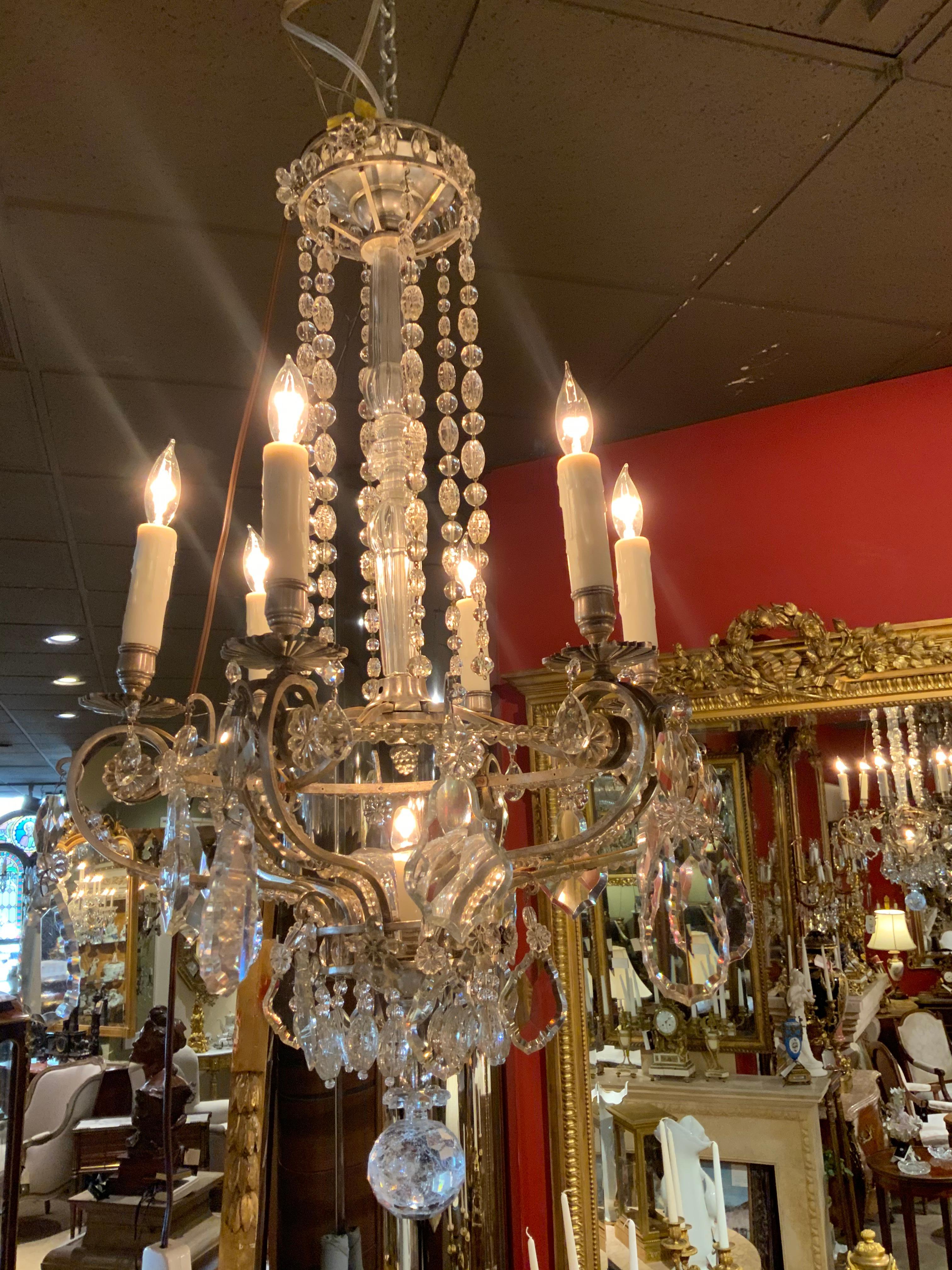 French silver and crystal chandelier with six lights on a beaded ring at the perimeter and one central light
That is  surrounded by a crystal bobéches. Crystal drops in a
Horizontal line Extend from the upper canopy.