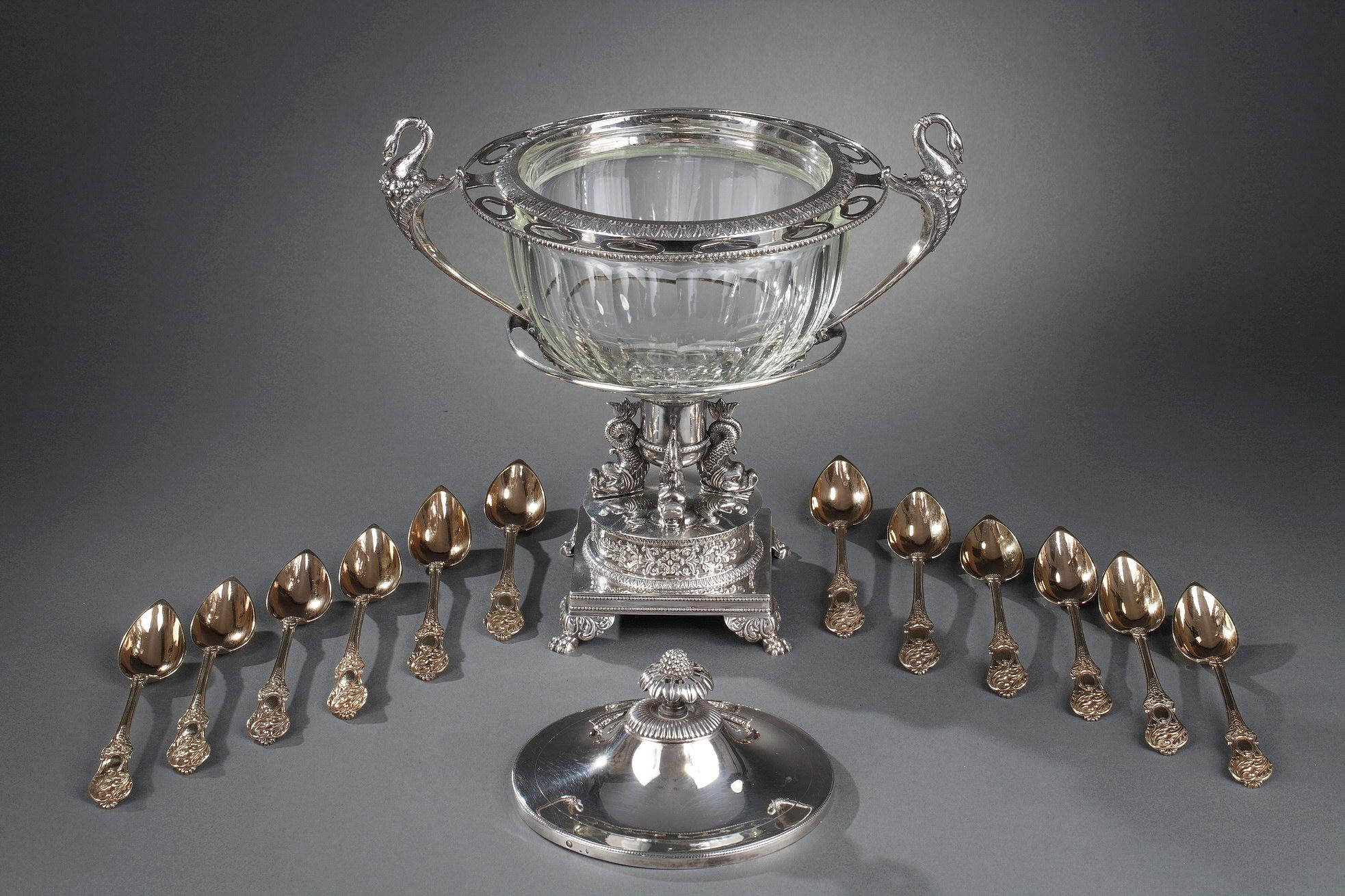 Silver and cut-crystal confiturier in Medici-shape decorated with two handles with floral motifs and volutes end in a swan's head. .The silver frame is adorned with laurel leaves and stylized palmettes. The confiturier dish rests on a raised foot