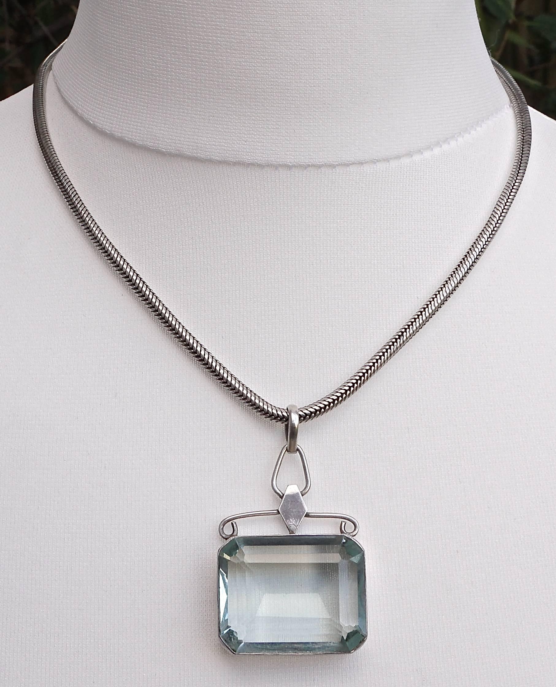 Vintage silver necklace with a large emerald cut glass pendant. The beautiful pale aqua stone measures 2.8cm, 1.1 inch, by 2.3cm, .9 inch, and is held in a simple hand forged setting, depth 7mm, .27 inch. The heavy silver snake chain has an ornate
