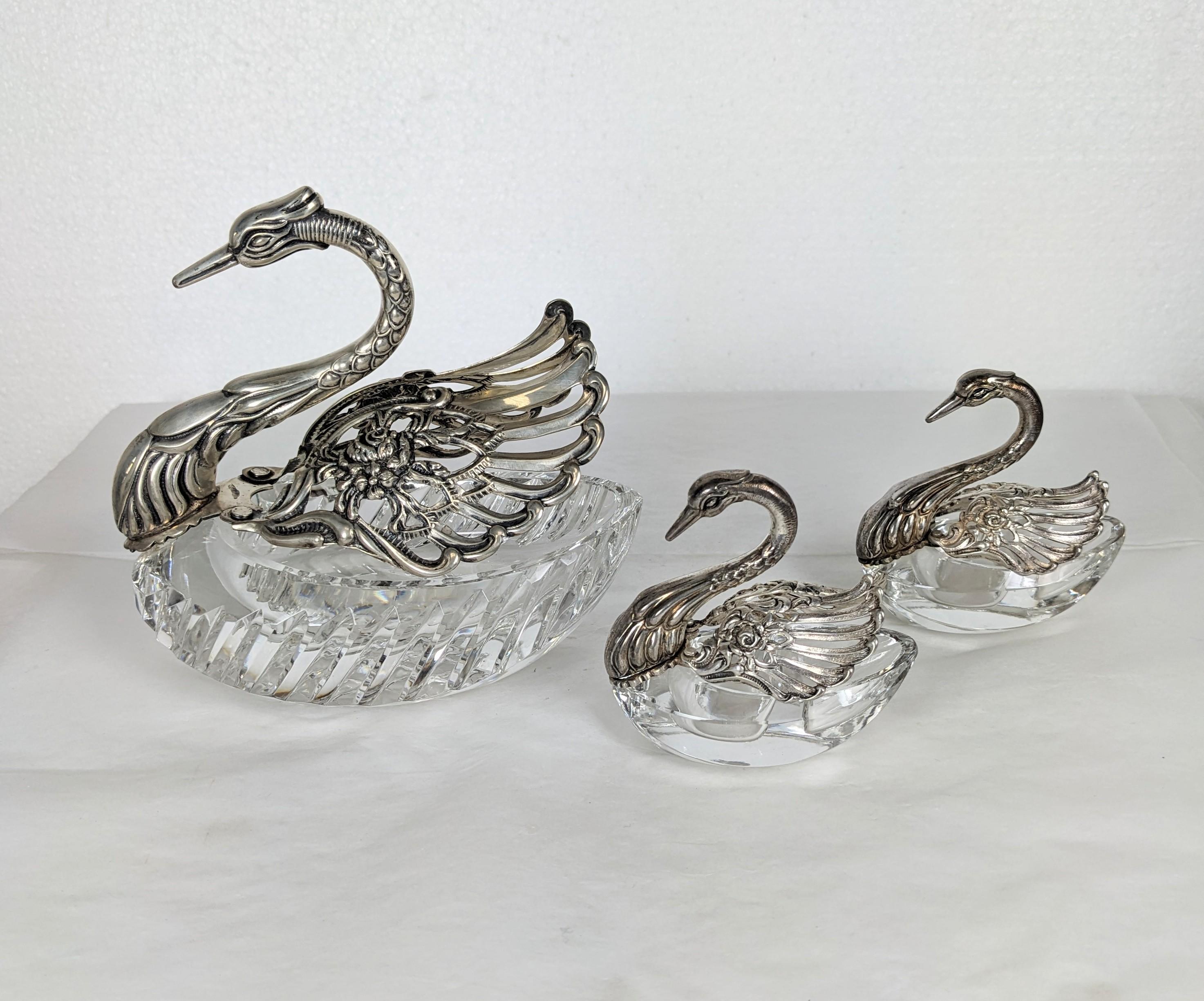 Set of 3 swan form salts from the early half of the 20th Century. One large master salt with 2 smaller salts with crystal bases and 835 grade pierced silver wings decorated with roses. The smaller salts are divided with salt and pepper wells where