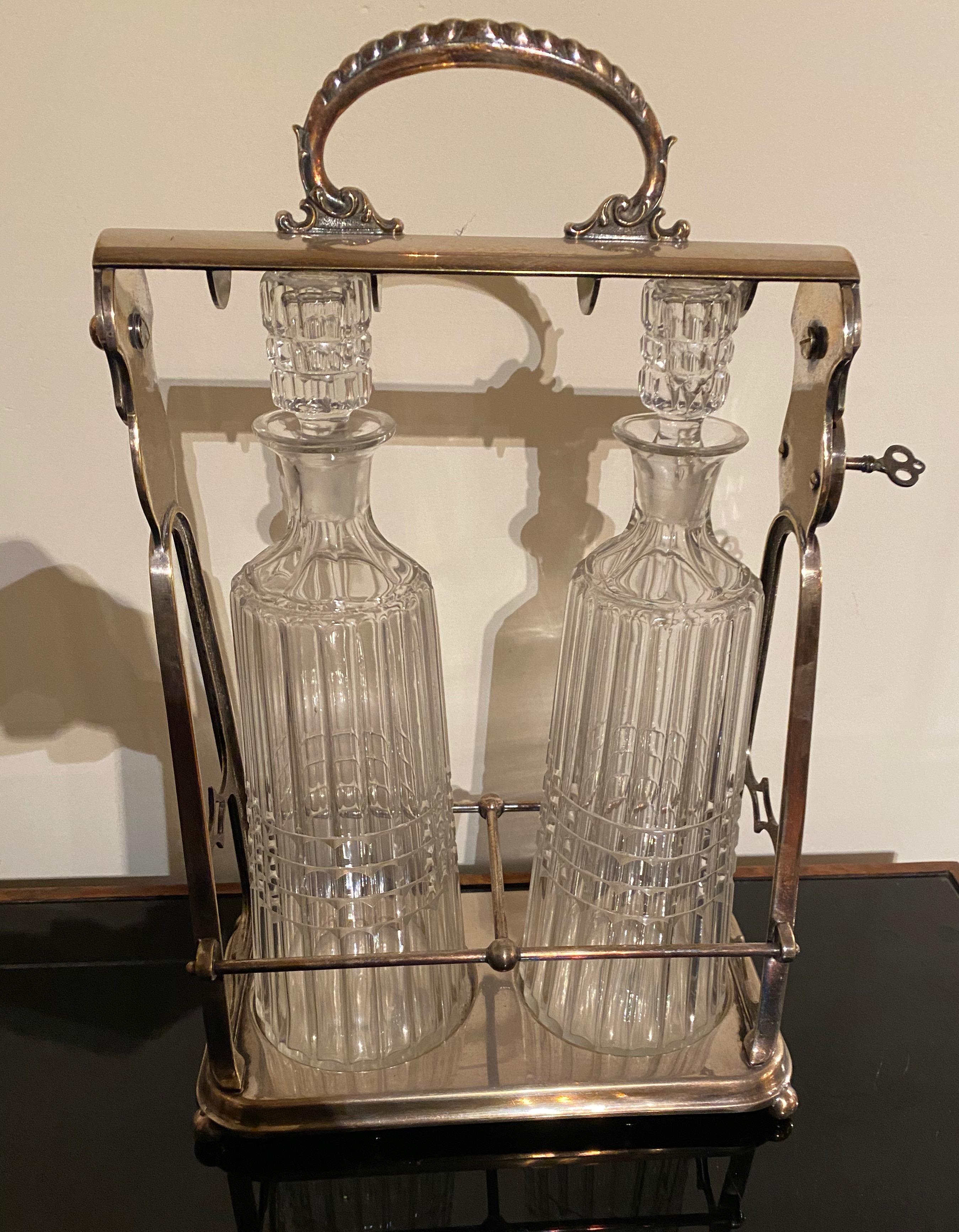 A silver locking tantalus with ribbed crystal decanters to display and serve fine liquors. This uniquely designed piece holds two separate bottles and opens to show them off. Faceted crystal knobs top, each bottle is nestled in a shaped silverplate