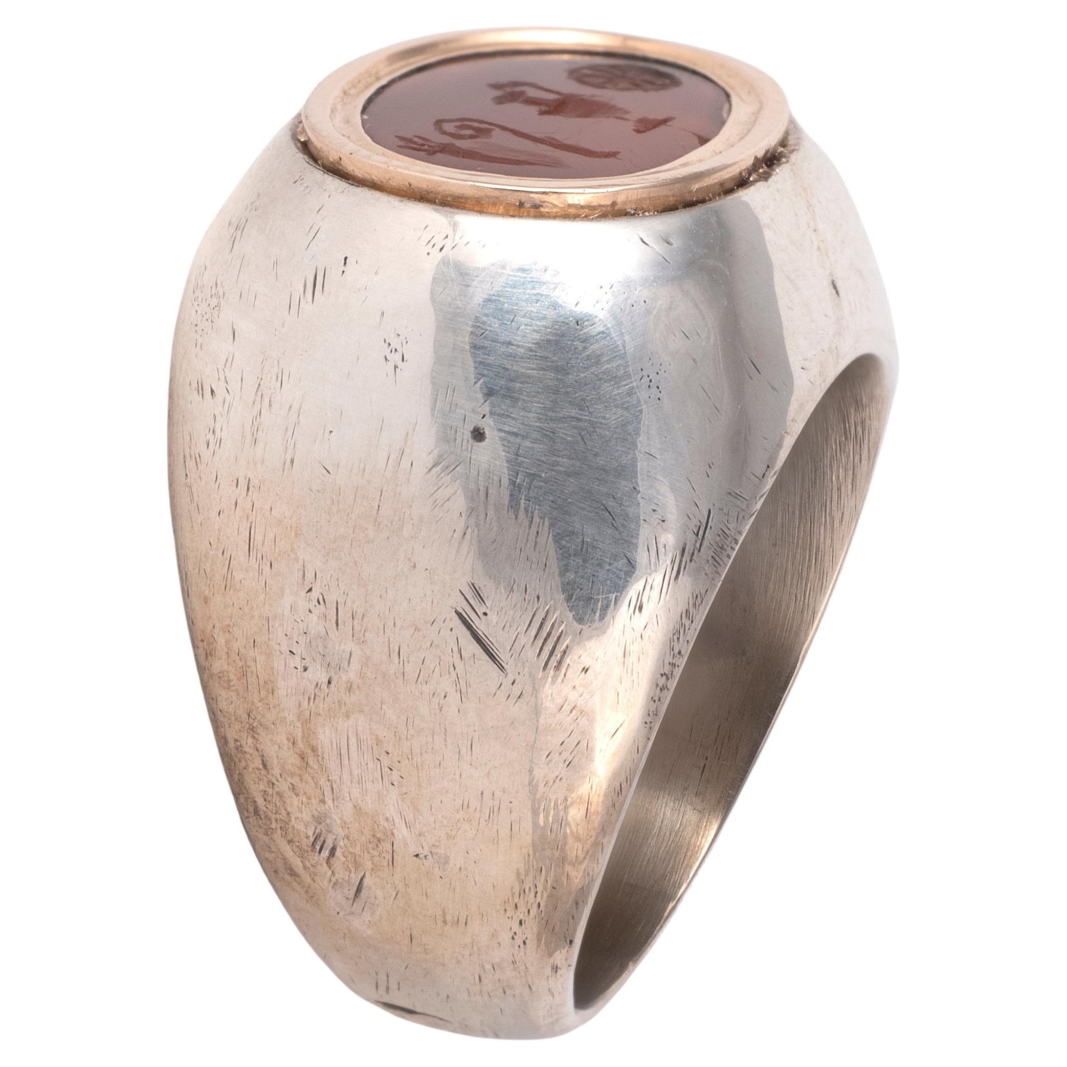 La bague en argent et en or est ornée d'une intaille en cornaline présentant quatre symboles religieux liés au christianisme : le feu, un bâton d'évêque, l'ampoule du Christ et une hostie eucharistique.

Poids : 16,89 g.
Taille : 8 3/4
Taille de la