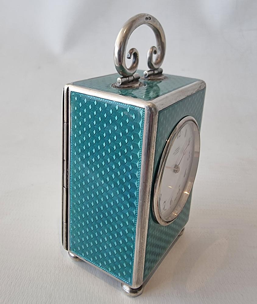 A fine miniature silver and teal blue guilloche enamel carriage or boudoir clock, retailed by Asprey's. White enamel dial with arabic numerals, and gold hands, marked under 12 o clock, 'Asprey Bond Street London'. Numerous silver marks including on