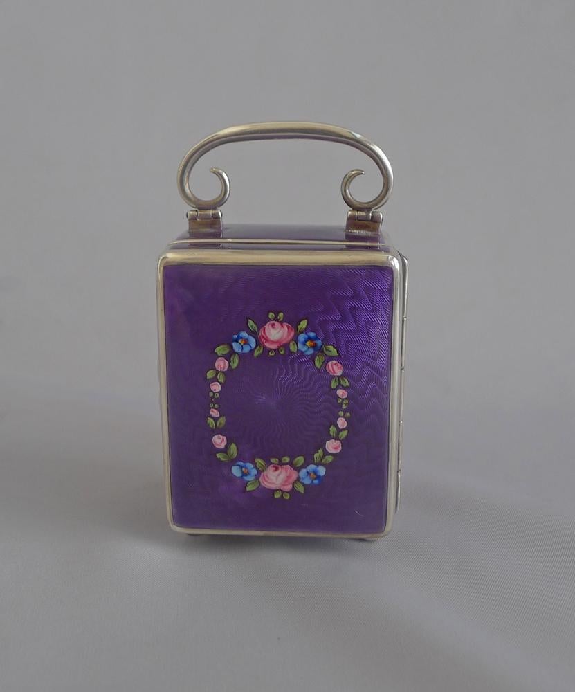 A very fine Swiss Silver and purple guilloche enamel miniature travel clock by the Geneva Clock Company. The rectangular case with purple sunburst guilloche enamel on 5 sides, on four silver bun feet, and with scrolling handle. The white enamel dial