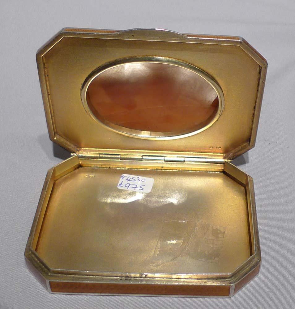 A silver and guilloche enamel snuff box of rectangular form with canted corners decorated with amber guilloche enamel panels on an engine turned ground within white line enamel borders, the hinge lid inset with a carved shell cameo oval panel.
