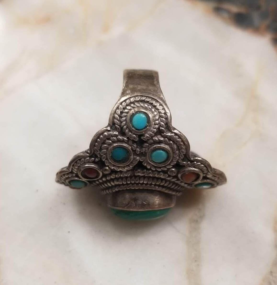 This silver gem pendant ring is adorned with a mesmerizing Malachite gem at its heart. Surrounding the central beauty are smaller Turquoise and Jasper gems, creating an intricate, nature-inspired design. This exquisite piece seamlessly blends