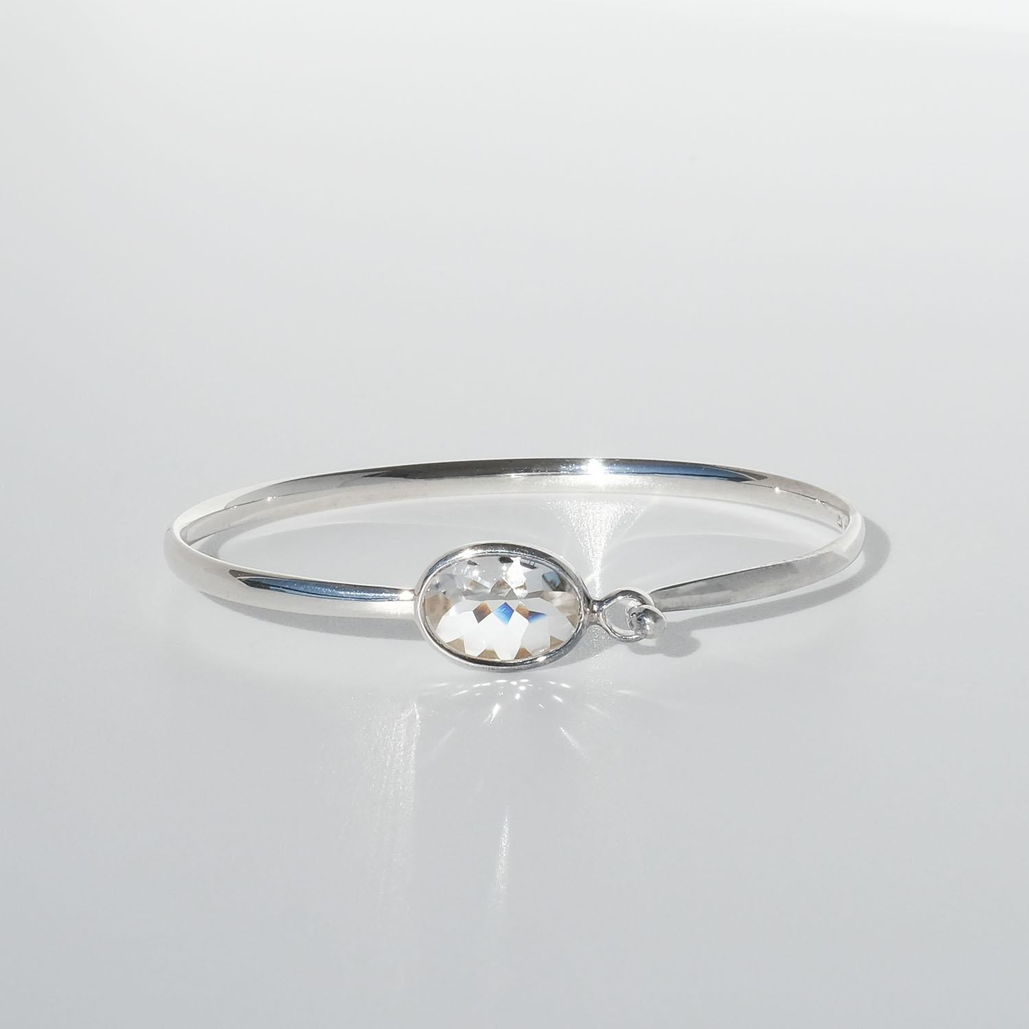 This sterling silver bracelet is adorned with an oval shaped rock crystal. The design generates a kaleidoscope effect when the light hits the rock crystal, creating a mixture of colours. The bracelet closes with a side hook clasp.

This bracelet is