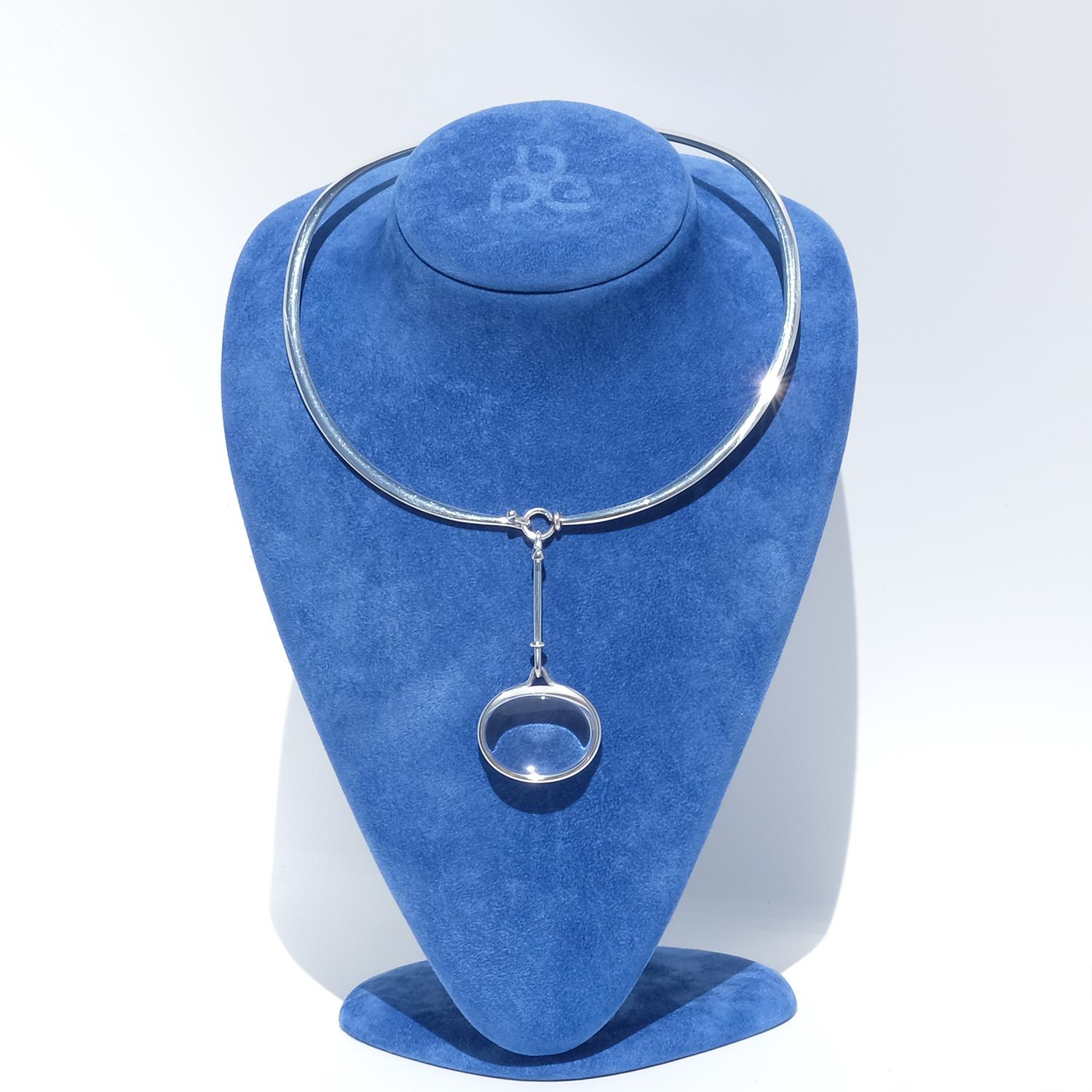 Diseñadora: Vivianna Torun Bülow-Hübe (1927-2004) para Georg Jensen (anillo para el cuello nº 410 / colgante nº 311C).

Este anillo vintage para el cuello está fabricado en plata pulida con una distintiva forma ovalada ancha, suavemente elevada en