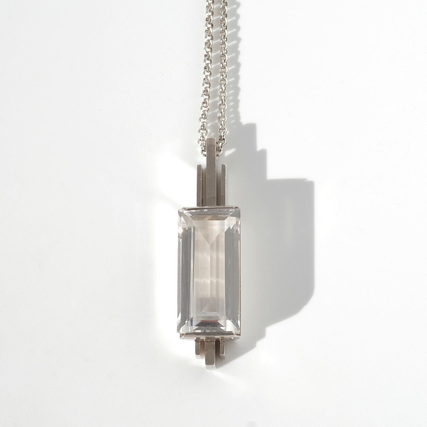 Questa collana in argento presenta un ciondolo di grande effetto con un cristallo di rocca rettangolare in un'incastonatura pulita e geometrica, che riflette le linee audaci e la simmetria caratteristiche dello stile Art Déco. Il ciondolo è