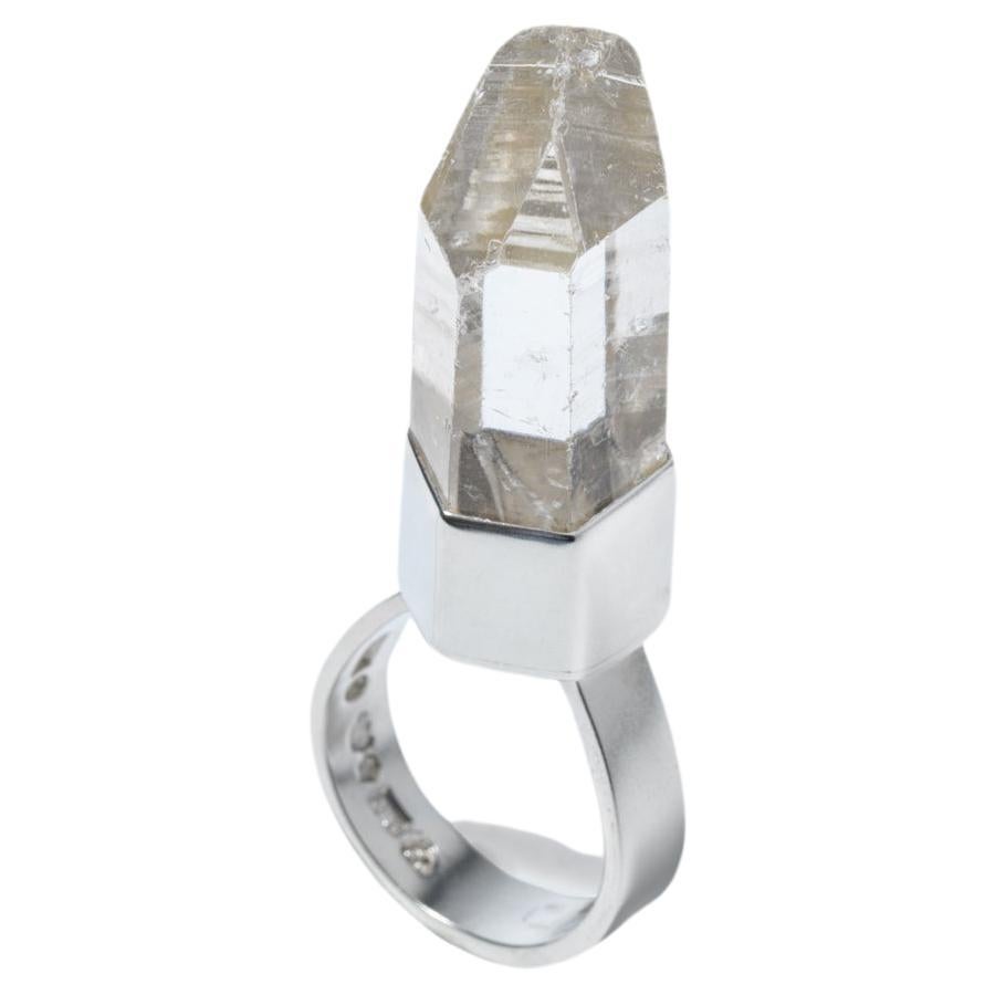 This ring features a striking fantasy cut rock crystal that resembles a spaceship, perched atop a hexagonal setting which gives it a unique geometric appeal. The silver shank of the ring is robust and prominent, drawing attention to the intricate