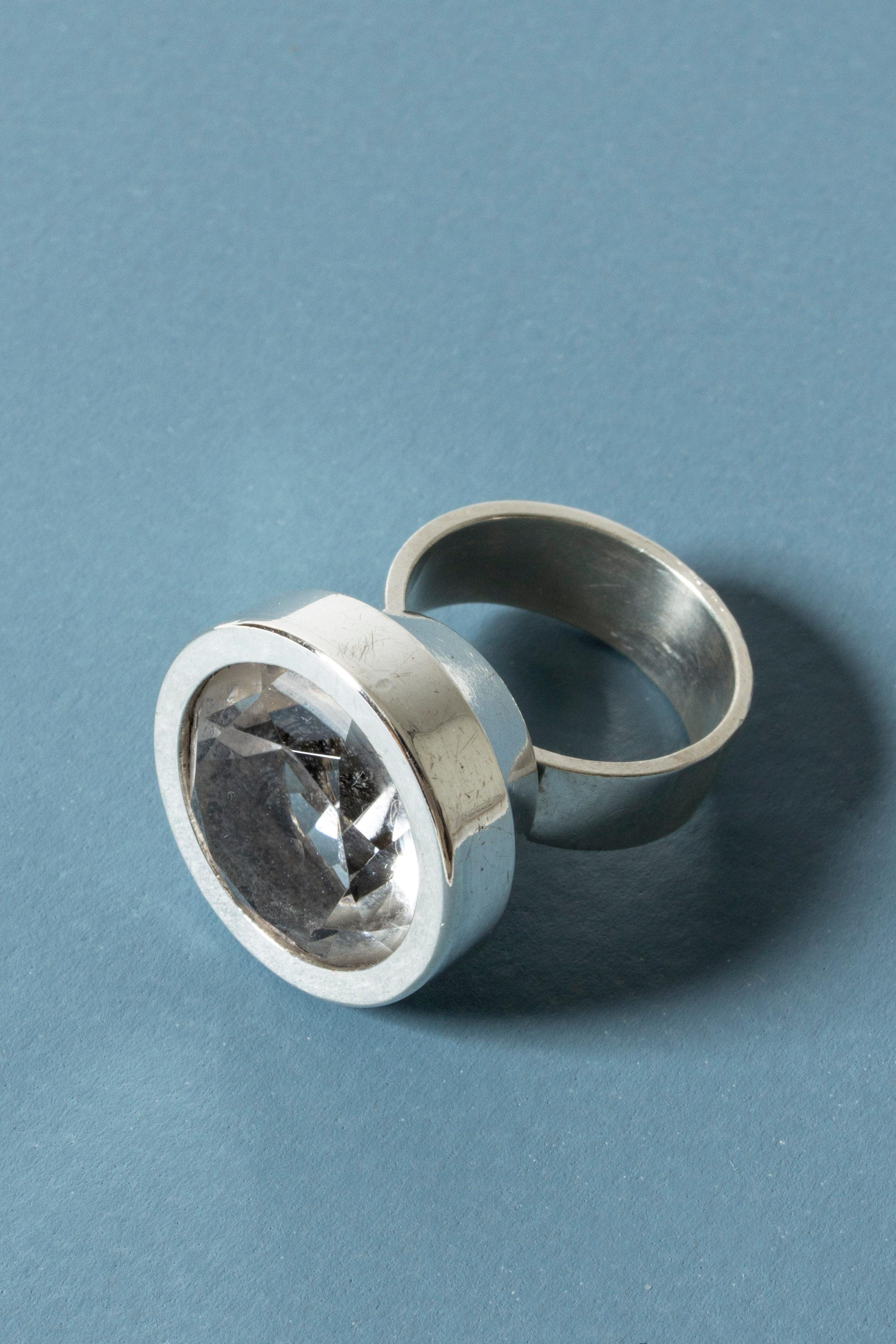 Amazing silver ring by Elis Kauppi, with a large rock crystal stone set in a smooth round frame. Very nice sheen in the stone from the facets.