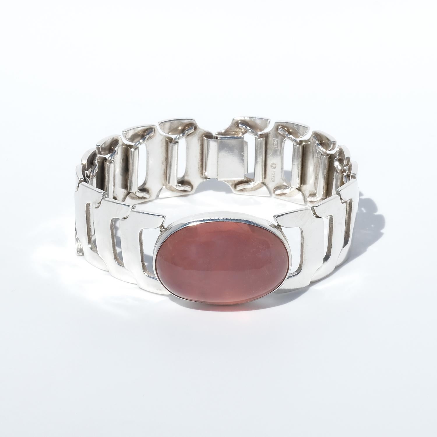 Questo bracciale vintage è realizzato in argento sterling e ha come centro un quarzo rosa tagliato a cabochon. Il quarzo rosa è incastonato in una lunetta liscia, che mette in mostra la sua morbida e traslucida tonalità rosa con profondità e