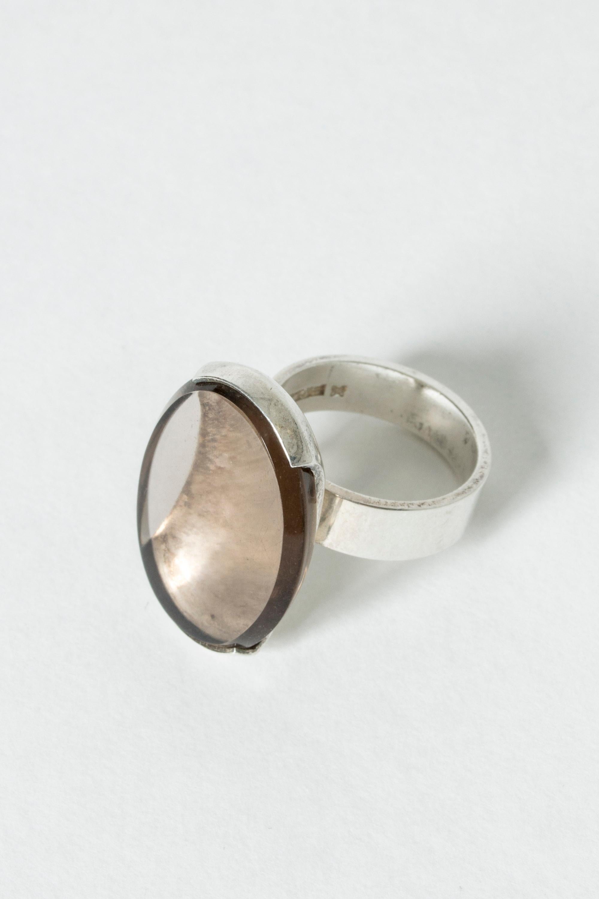 Amazing silver ring by Elis Kauppi, with a large, almond shaped smoke quartz stone. The silver setting elevated the stone so that light comes in from underneath and the sides. Beautiful optical effect.