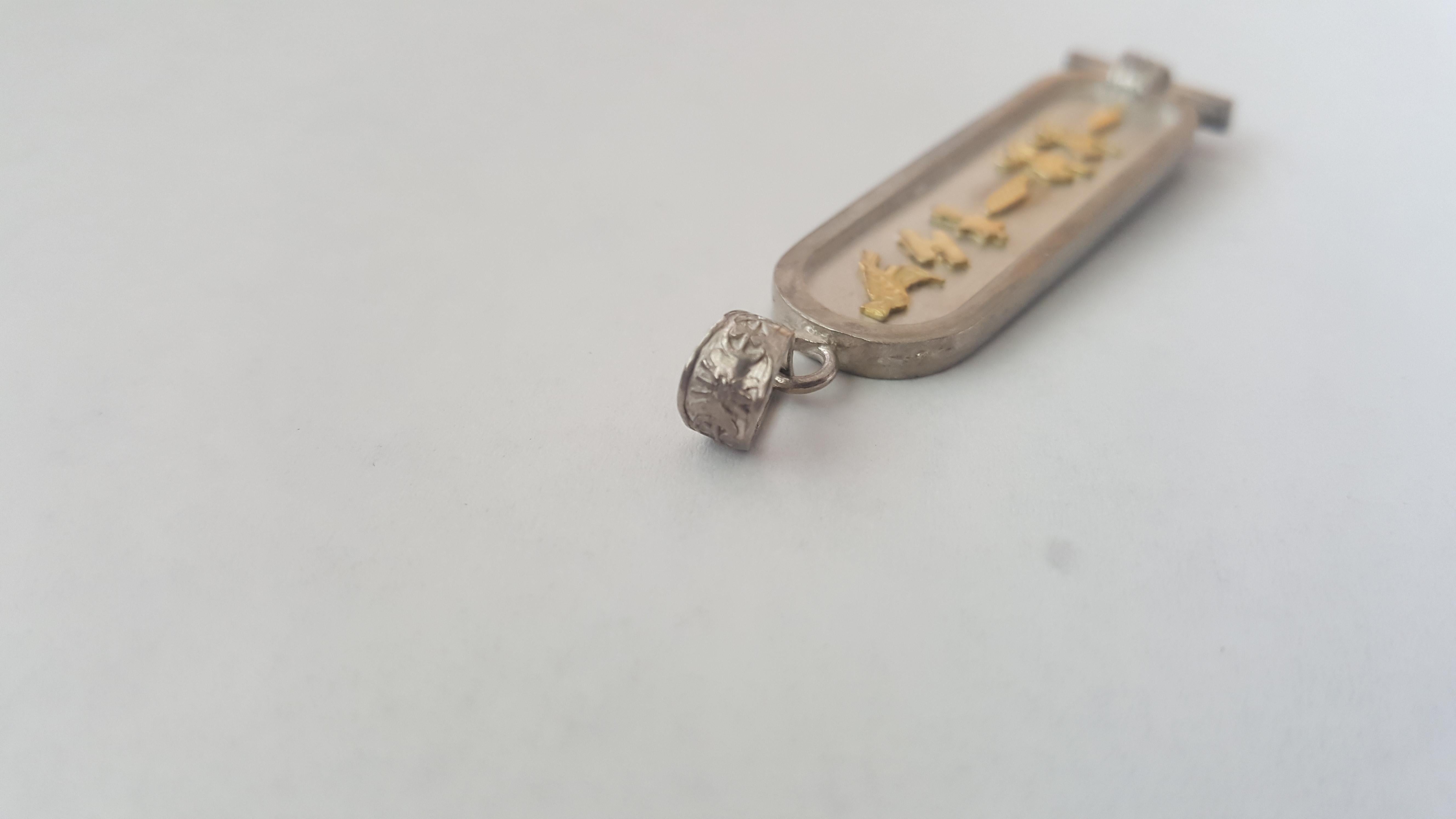 Silver and Solid 14kt Yellow Gold Michelle Pendant with Egyptian Lettering. This pendant is 10 grams in weight, has a satin textured finish and 46mm x 14mm x 2.75 mm in size.

Rock N Gold Creations is a full-service, award-winning fine jeweler