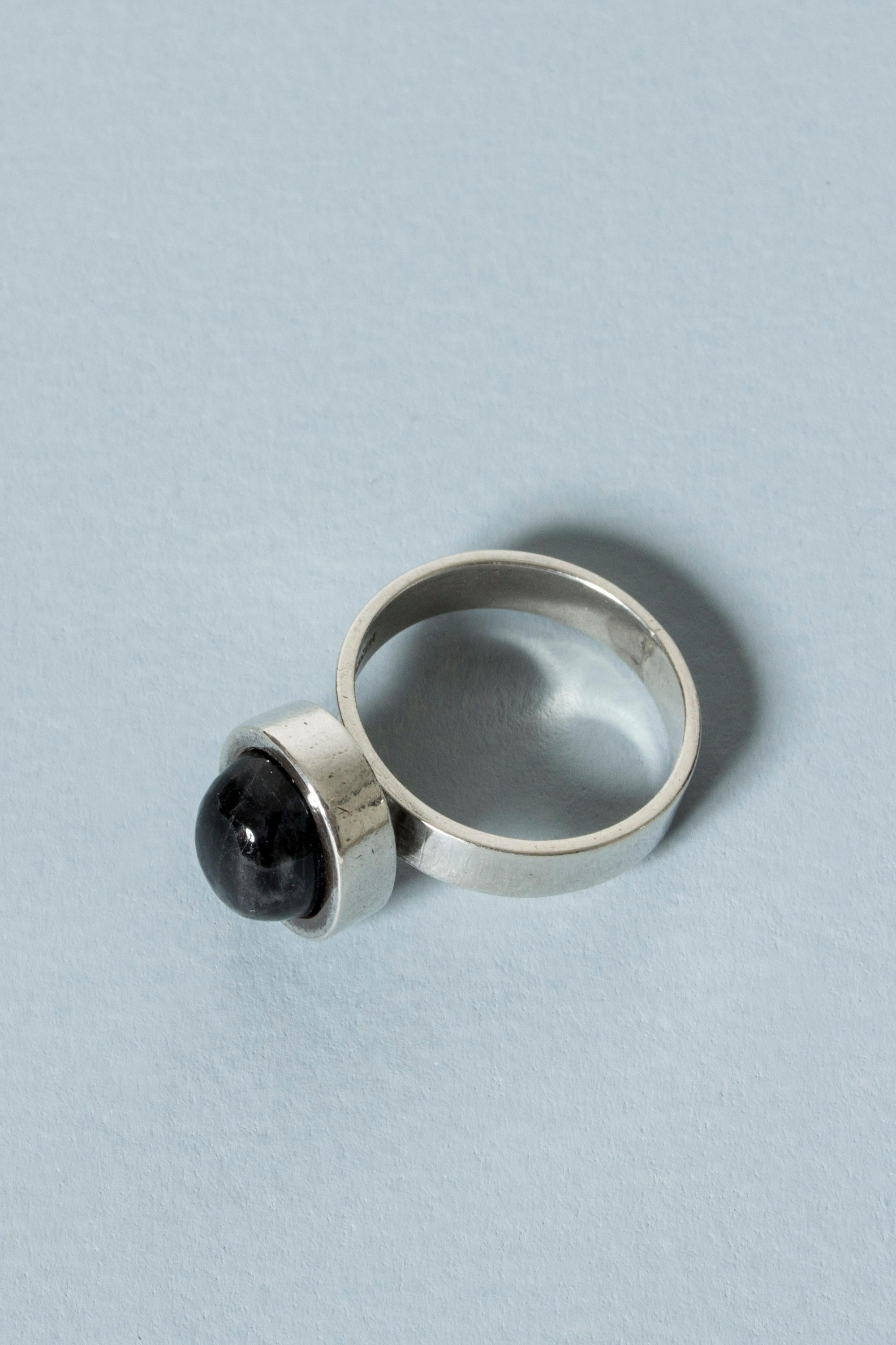 Elegant silver ring from Valo Koru, with an oval, cabochon cut spectrolite stone. The stone and its frame seems to float slightly above the band. Subtle sheen in the stone.

