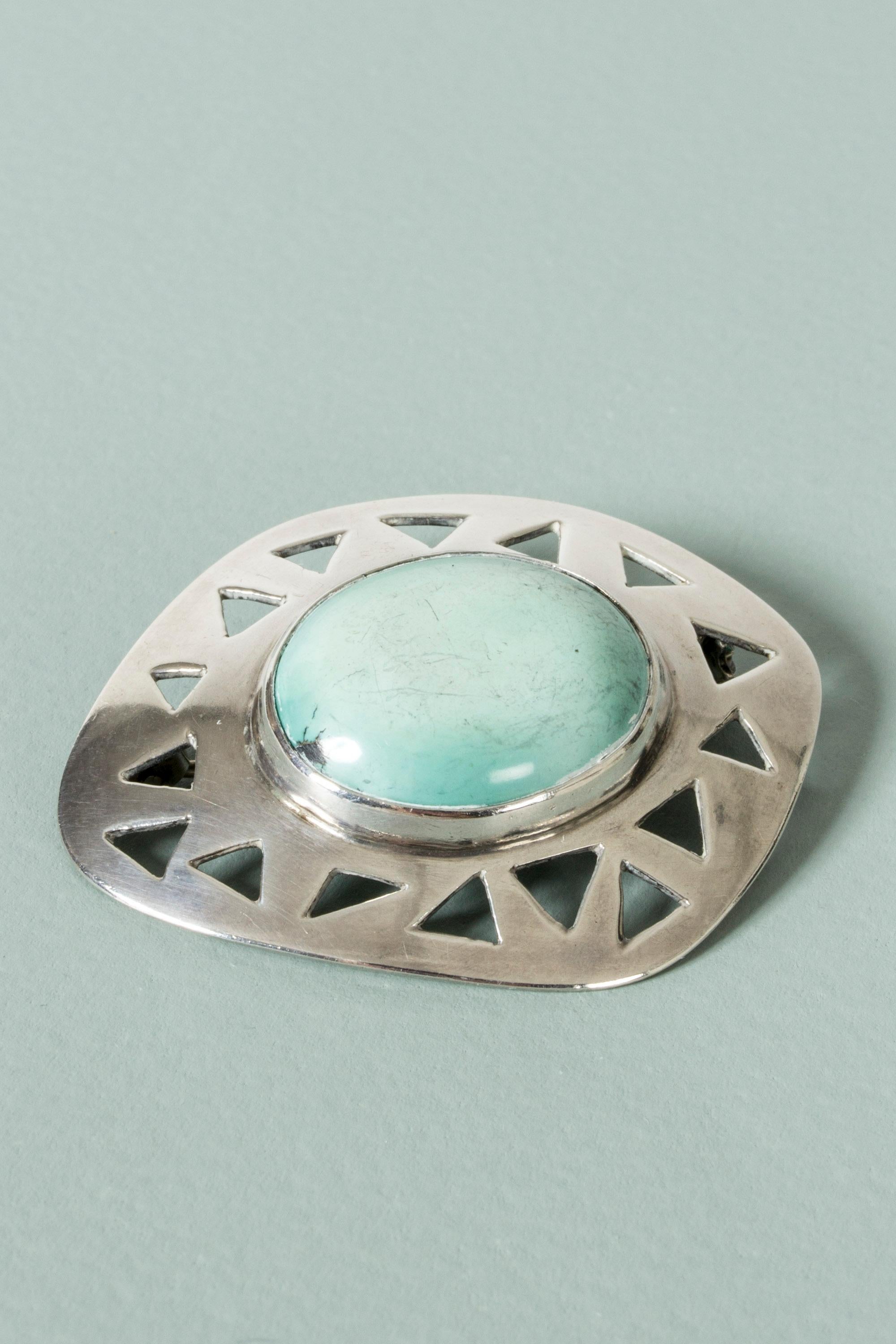 Cool silver brooch from Michelsen, in an asymmetric design with a cut-out pattern of triangles. Large, pale green turquoise stone in the middle. A very graphic 1950s design.