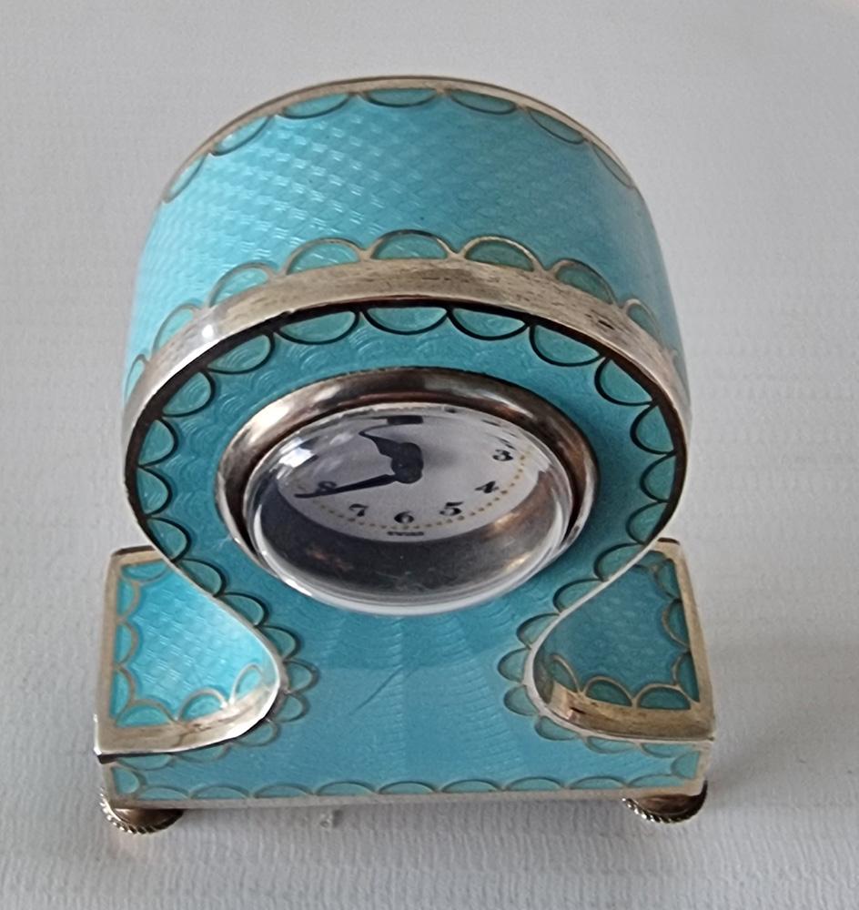 A silver and turquoise guilloche enamel balloon shaped sub miniature carriage or boudoir clock. An unusual shape clock for a sub miniature, with white enamel dial and arabic numerals, dial marked 'Swiss'. The underside and back of case marked with