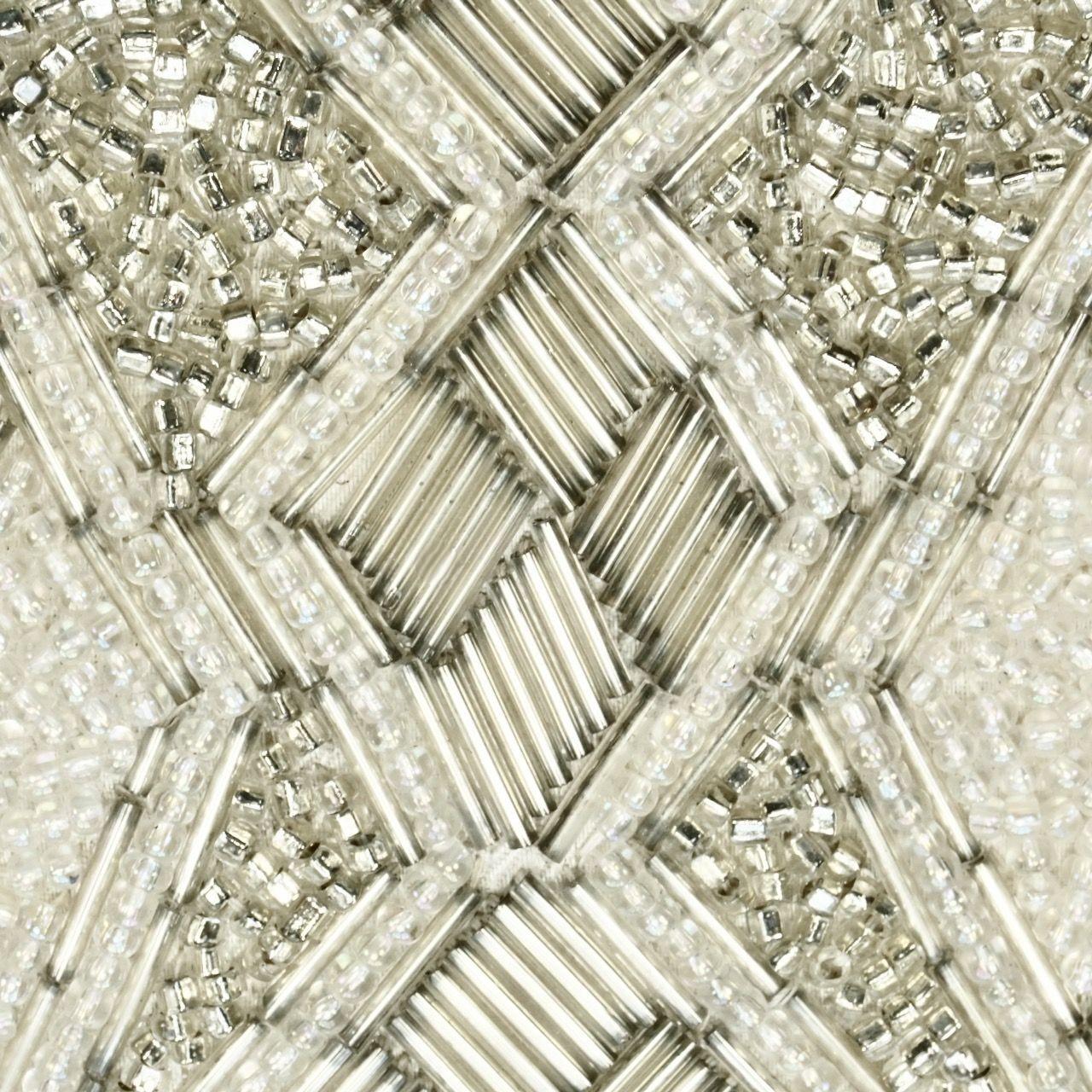 Shimmering silver and white diamond design beaded bag with silver tone fittings. Measuring length at the base 17.5 cm / 6.8 inches by width 10.8 cm / 4.25 inches, and depth 3.5 cm / 1.37 inches. The handle drop is 12 cm / 4.7 inches. The bag closes