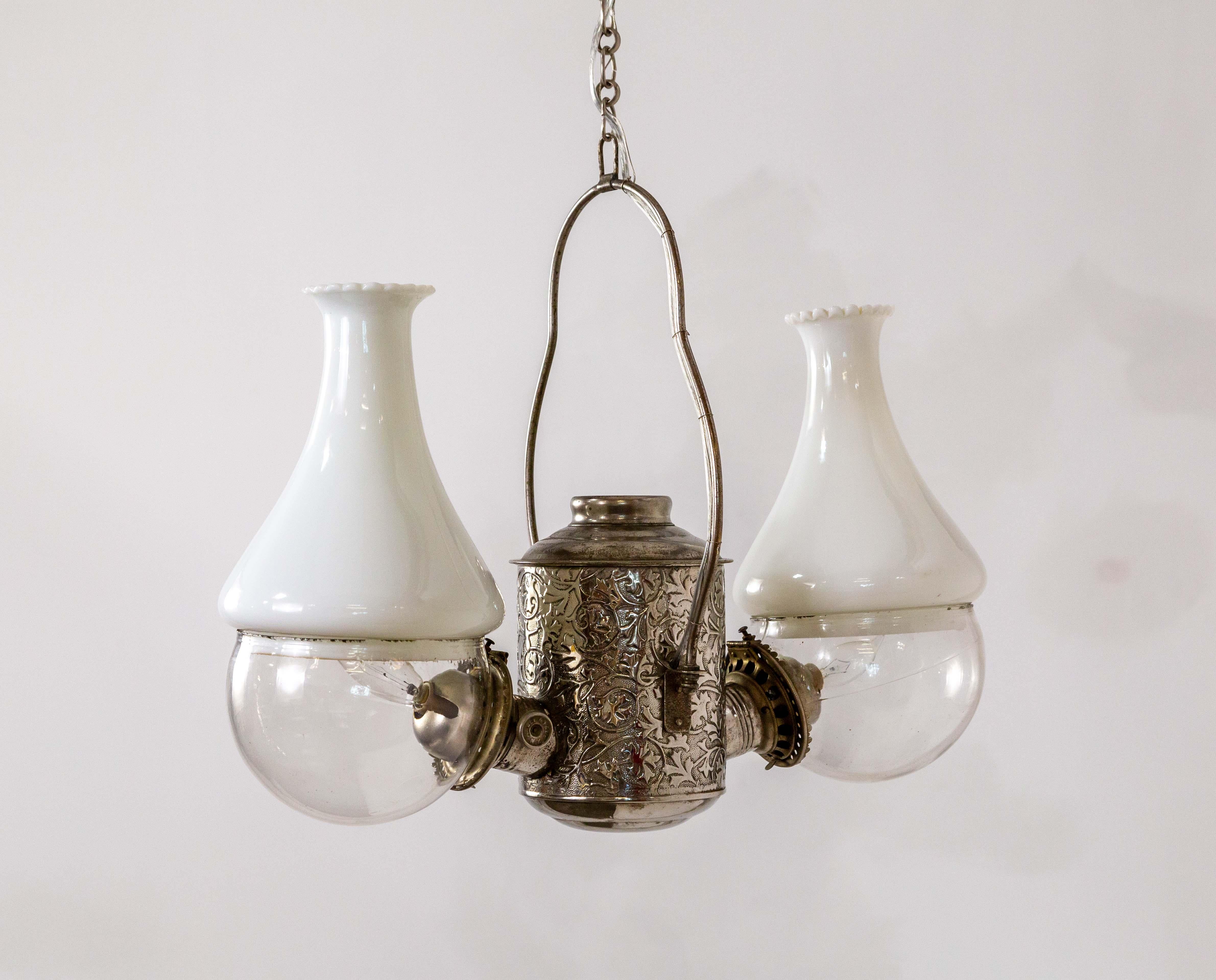This is an 1890s double light, hanging fixture by The Angle Lamp Co. that was originally lit by kerosene, and is now electrified. Its oil lamps were unique, with the burner on the side at nearly a 90-degree angle to the lamp's body. It has the