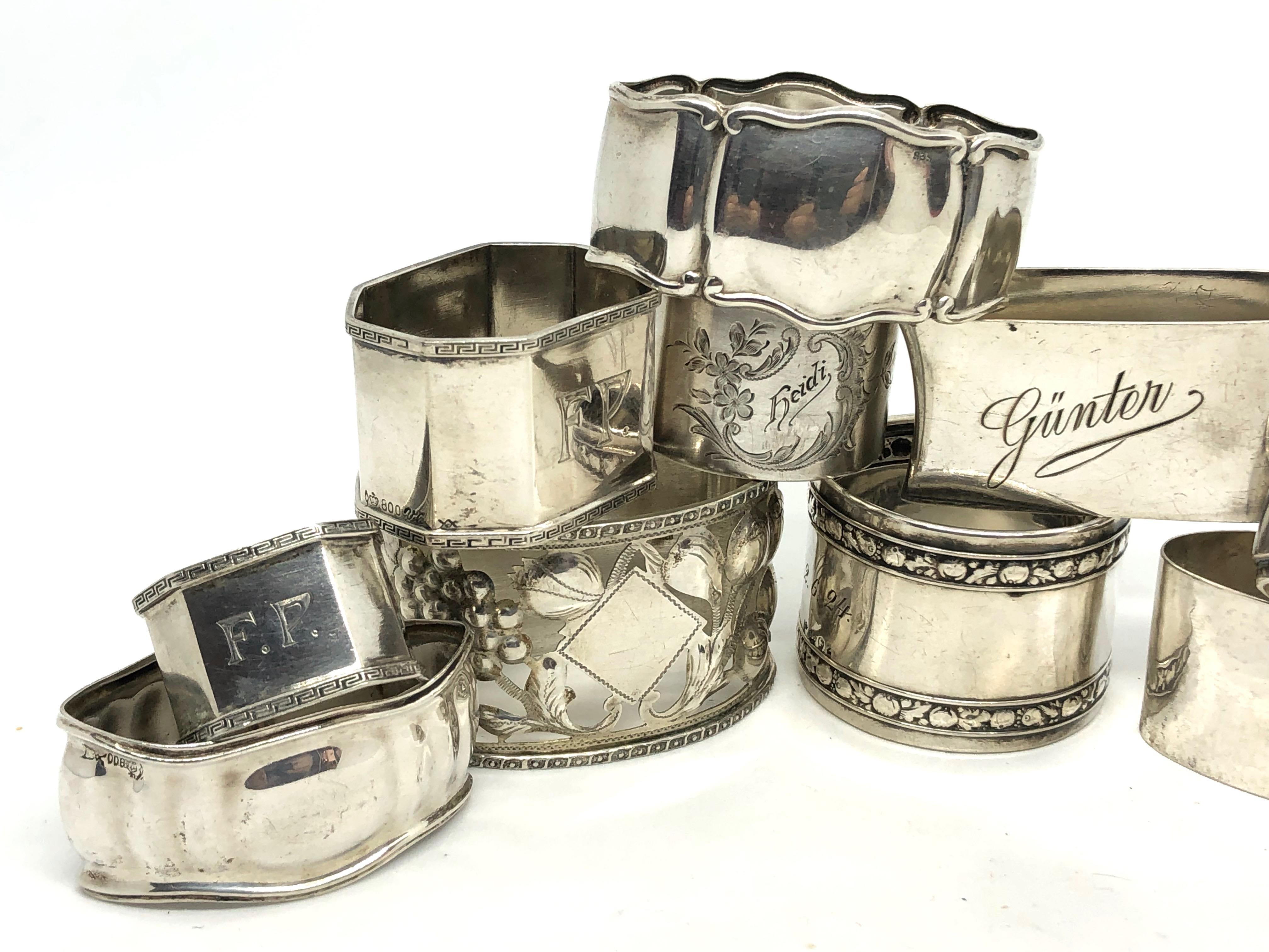A mixed set of ten silver alloy napkin rings, circa 1924-1947, various makers. A nice selection of barrel, rectangular, paneled and round rings, one Art Nouveau one with fruit pattern engraved 14 on the backside (probably means 1914), ranging in