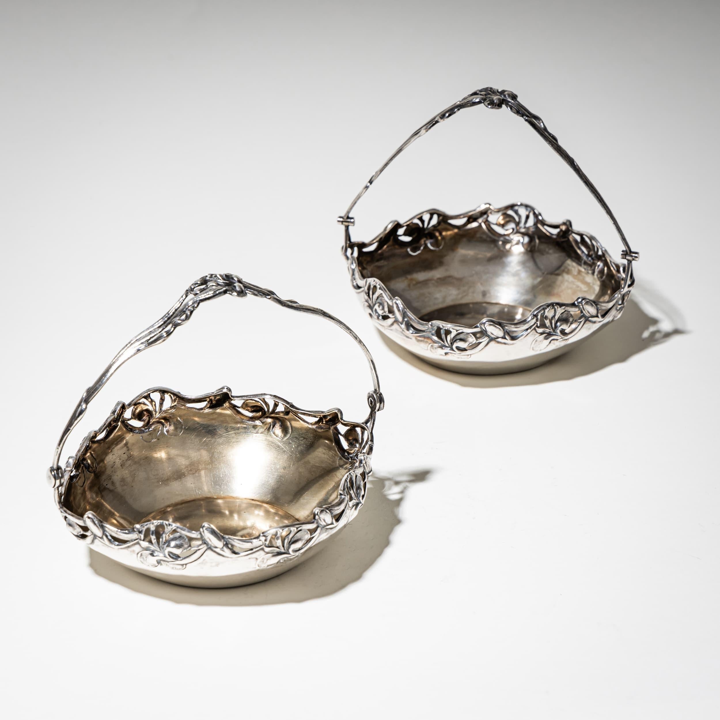 Coppia di eleganti ciotole in argento Art Nouveau con manici e bordi traforati ornati da motivi floreali stilizzati. Entrambi i pezzi recano il marchio della base, Silver 800, e il marchio del produttore Wilhelm Binder, Schwäbisch Gmünd. Pesi: 119 g