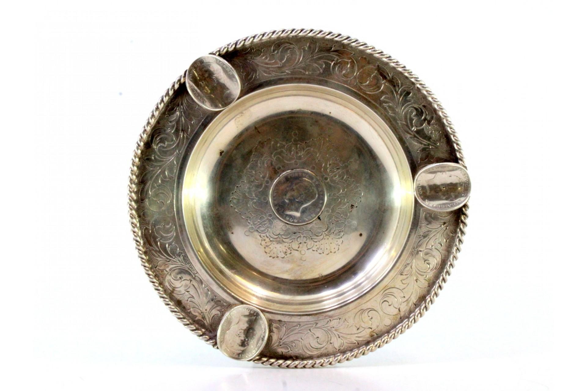 Description: Silver ashtray with corded friezes, engraved garlands and four inlaid coins of D. Luís. Metal: Silver. Origin: Portuguese. Mark: standing eagle. Weight: 174.91 grams. Dimensions: 14.5cmx14.5cm. Content: 833/1000. Assay Mark: Yes,
