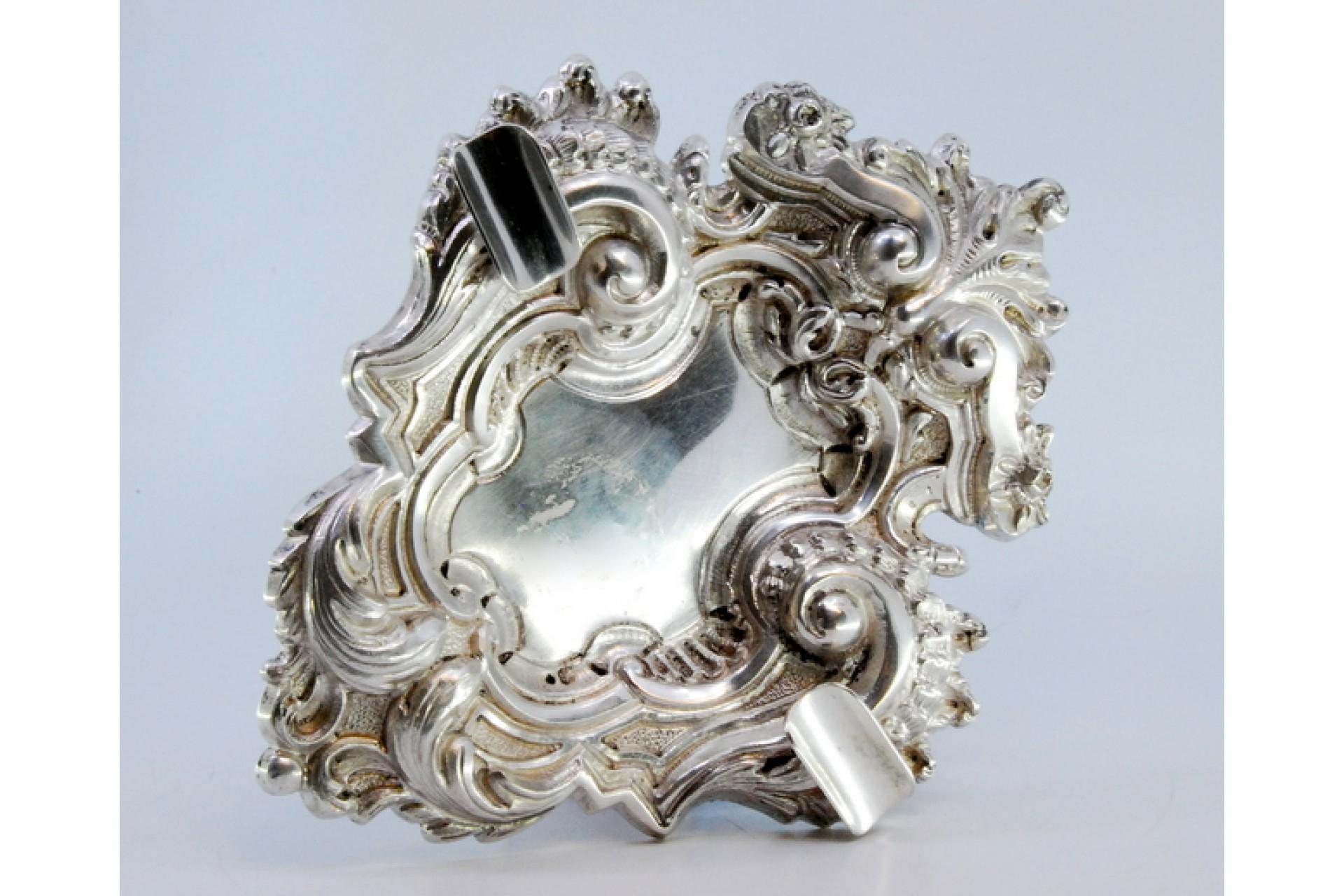 Description: Silver ashtray with high reliefs in the style of D. João V with two cigarette holders. Metal: Silver. Origin: Portuguese. Mark: standing eagle. Weight: 161.97 grams. Dimensions: 19x15cm. Content: 833/1000. Assay Mark: Yes, between 1938