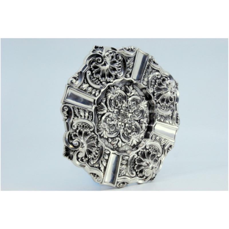 Description: Silver ashtray with shell-shaped reliefs and cigarette holders. Metal: Silver. Origin: Portuguese. Mark: Standing eagle. Weight: 252.91 grams. Dimensions: 18x18cm. Content: 833/1000. Assay Mark: Yes, 1938 and 1984. Additional