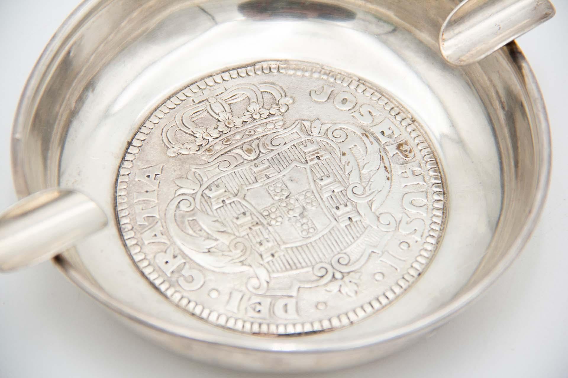 Description : Cendrier en argent avec les armoiries portugaises faisant allusion à I+I et deux porte-cigarettes. Métal : Argent. Origine : Portugais. Marque : javali I+I Titre. Poids : 112,07 grammes. Dimensions : 13..8cmx3.1cm : 13..8cmx3.1cm.