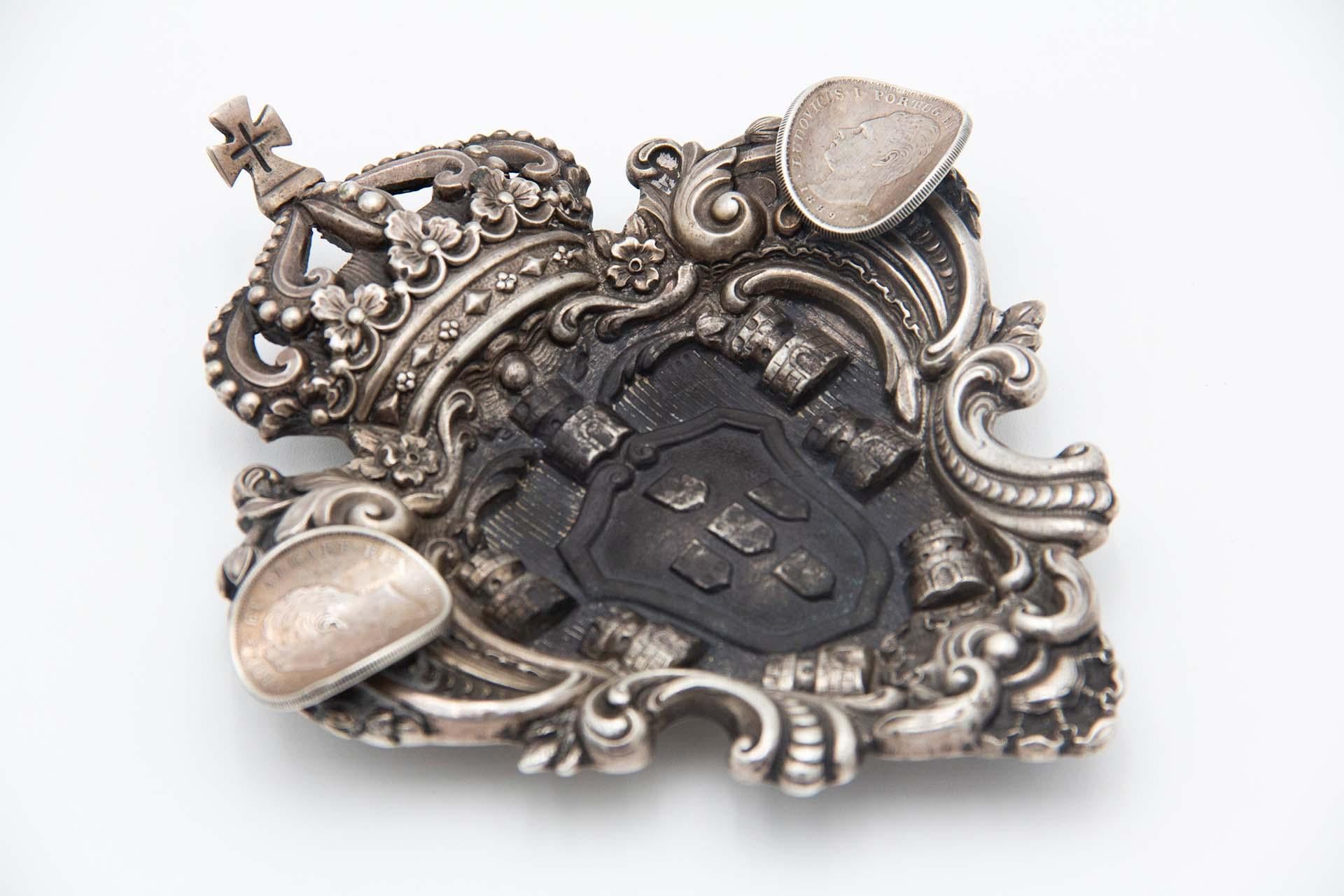 Description: Silver ashtray with the Portuguese Coat of Arms and two coins of D. Luís I of Portugal. Metal: Silver. Origin: Portuguese. Brand: boar II Title. Weight: 138.52 grams. Dimensions: 16.5cmx3cm. Content: 833/1000. Assay Mark: Yes, between