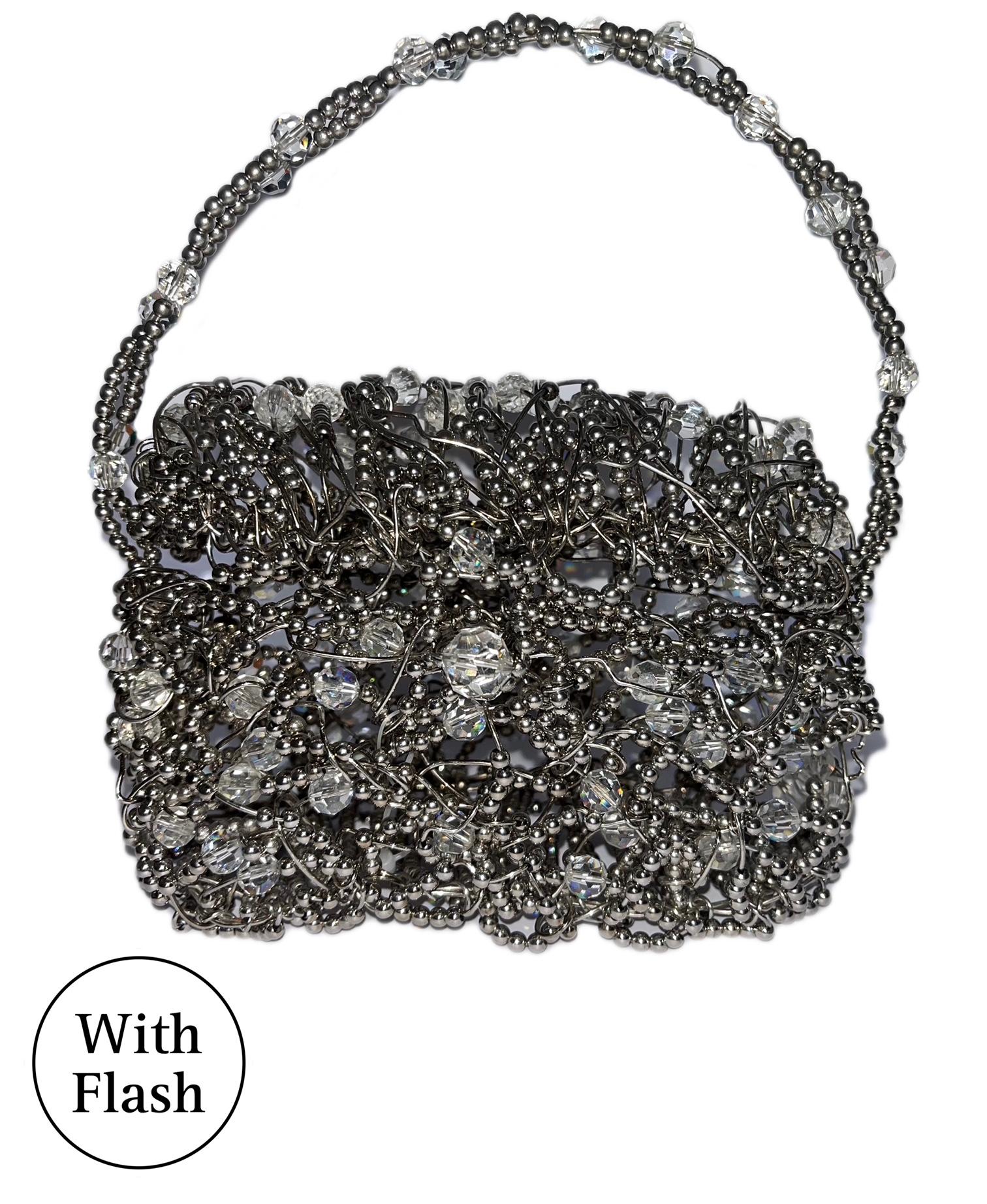 This beautiful vintage evening bag is a creation by Daniel Swarovski. The work done is an intricate design of woven silver-toned metal threads. Each threat has many silver-toned metal beads with crystal translucent round pearls. The locking system