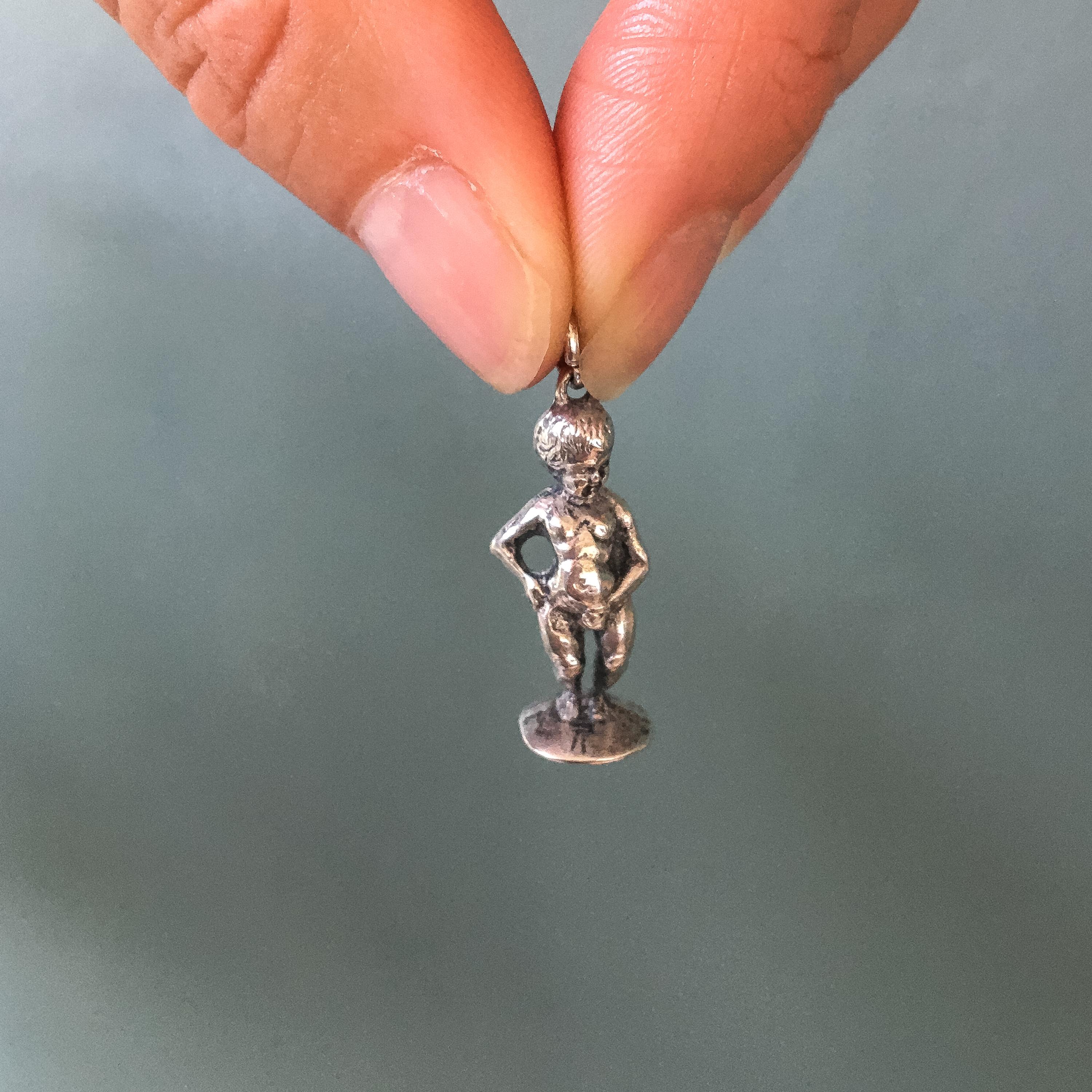 Er ist das Sinnbild für den rebellischen Geist der Stadt Brüssel. Sein Kleiderschrank zählt mehr als 900 Anzüge! Dieser belgische Manneken Pis-Charme im Vintage-Stil besteht aus Sterlingsilber und ist dreidimensional. Er kann aufrecht auf seinem