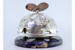 Silver bell with pierced angelic motifs on marble base