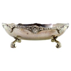 Bonboneiro en argent avec bord estampé et reposant sur quatre pieds à volutes.