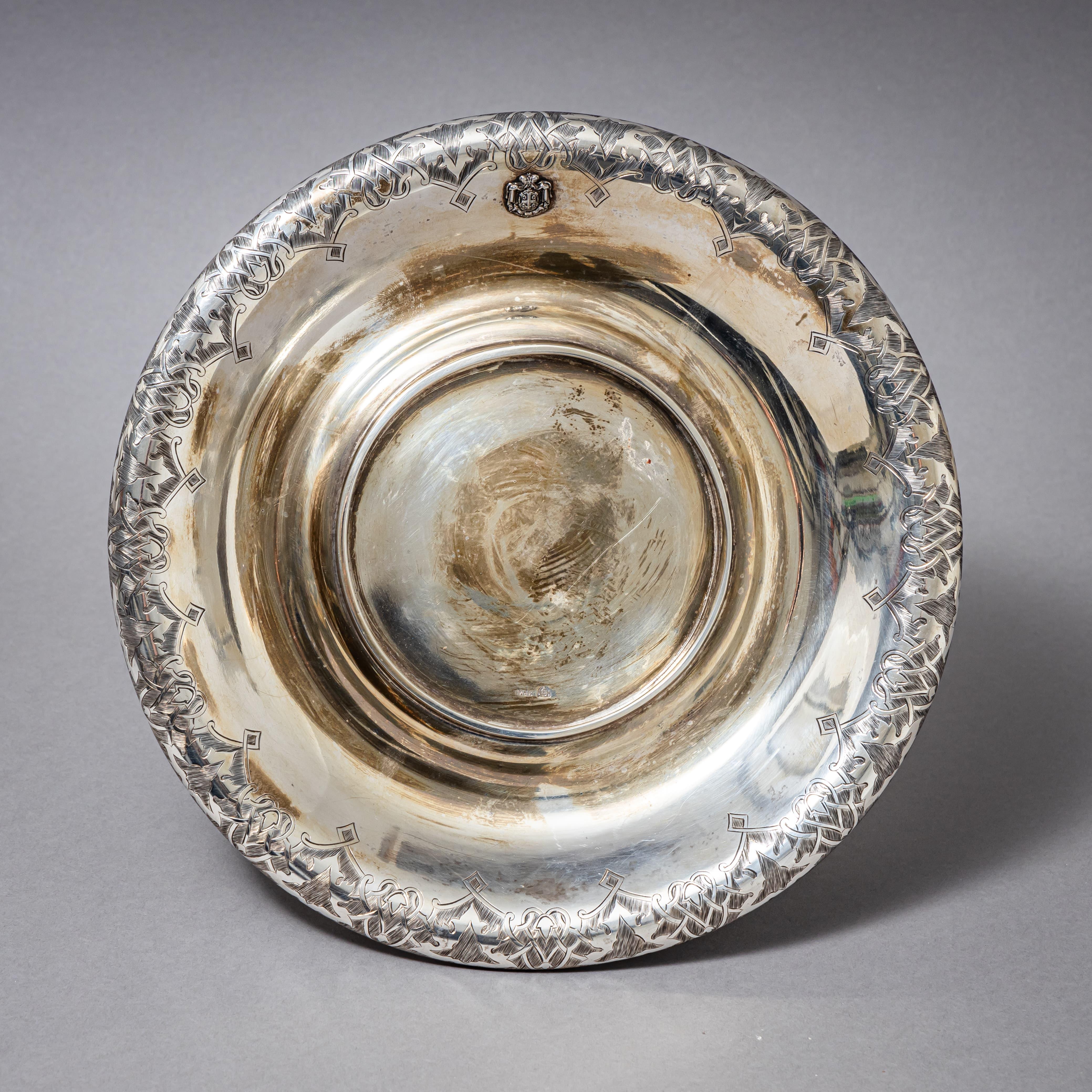 Finely crafted silver bowl featuring a chased rim and applied coat of arms on the body. The bowl rests on a molded, ebonized wooden base. Hallmarked on the interior with the maker’s mark M&K for Mayerhofer & Klinkosch, Vienna city mark, and the