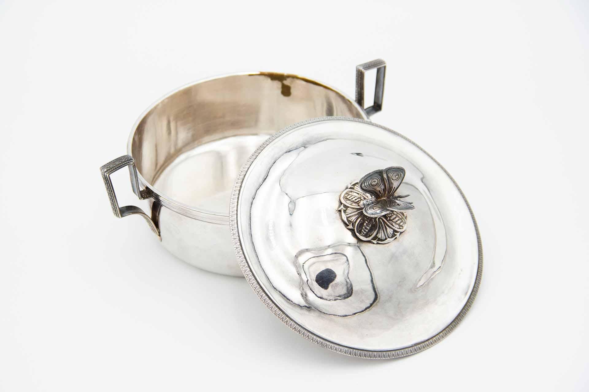 Description: Silver scullet with a perfectly shaped butterfly-shaped pommel on the removable lid, surrounding friezes and openwork handles. Metal: Silver. Origin: Dutch. Mark: Head of Minerva with helmet. Weight: 687.66 grams. Dimensions: