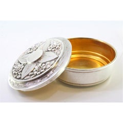Silver box for hosts with raised floral motifs on the lid and gold interior