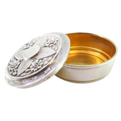 Silver box for hosts with raised floral motifs on the lid and gold interior