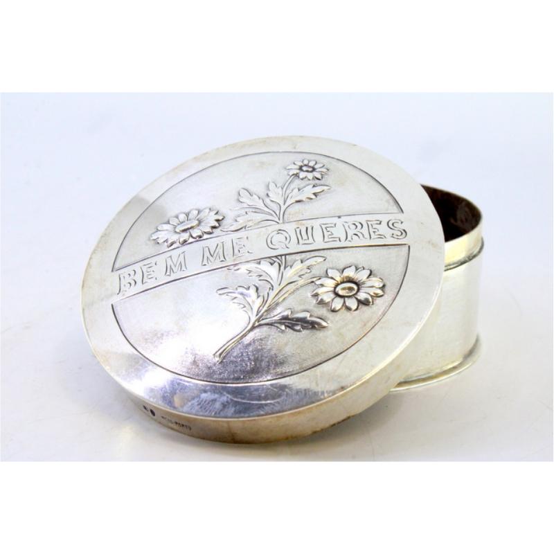 Description: Silver box for pins and needles with marigolds in relief on the removable lid. Metal: Silver. Origin: Portuguese. Brand: Javali II Title. Weight: 88.33 grams. Dimensions: 6.9cmx3.5cm. Content: 833/1000. Assay Mark: Yes, between 1887 and